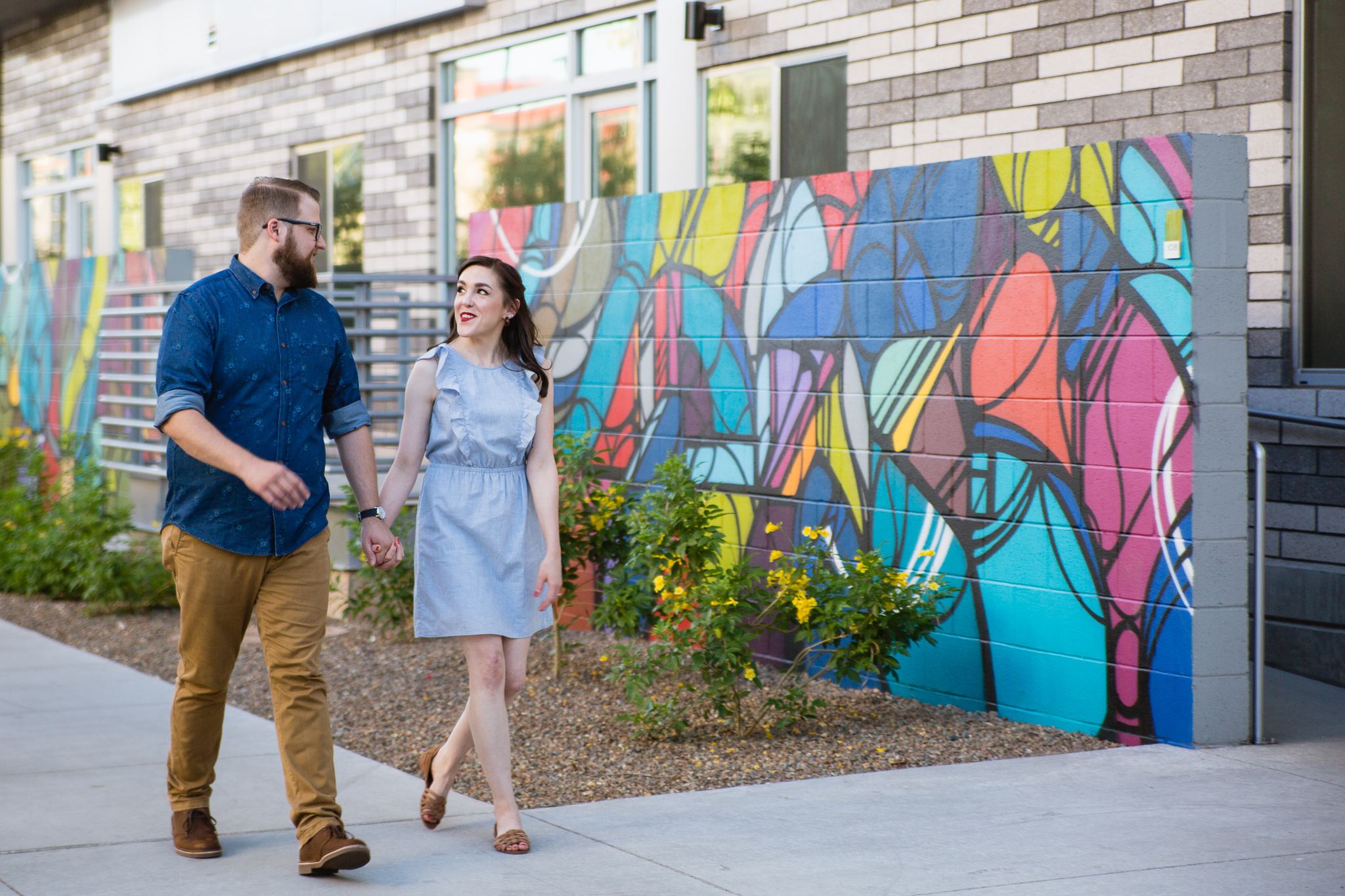Couple walking together during their downtown Phoenix engagement session by Arizona engagement photographer PMA Photography.