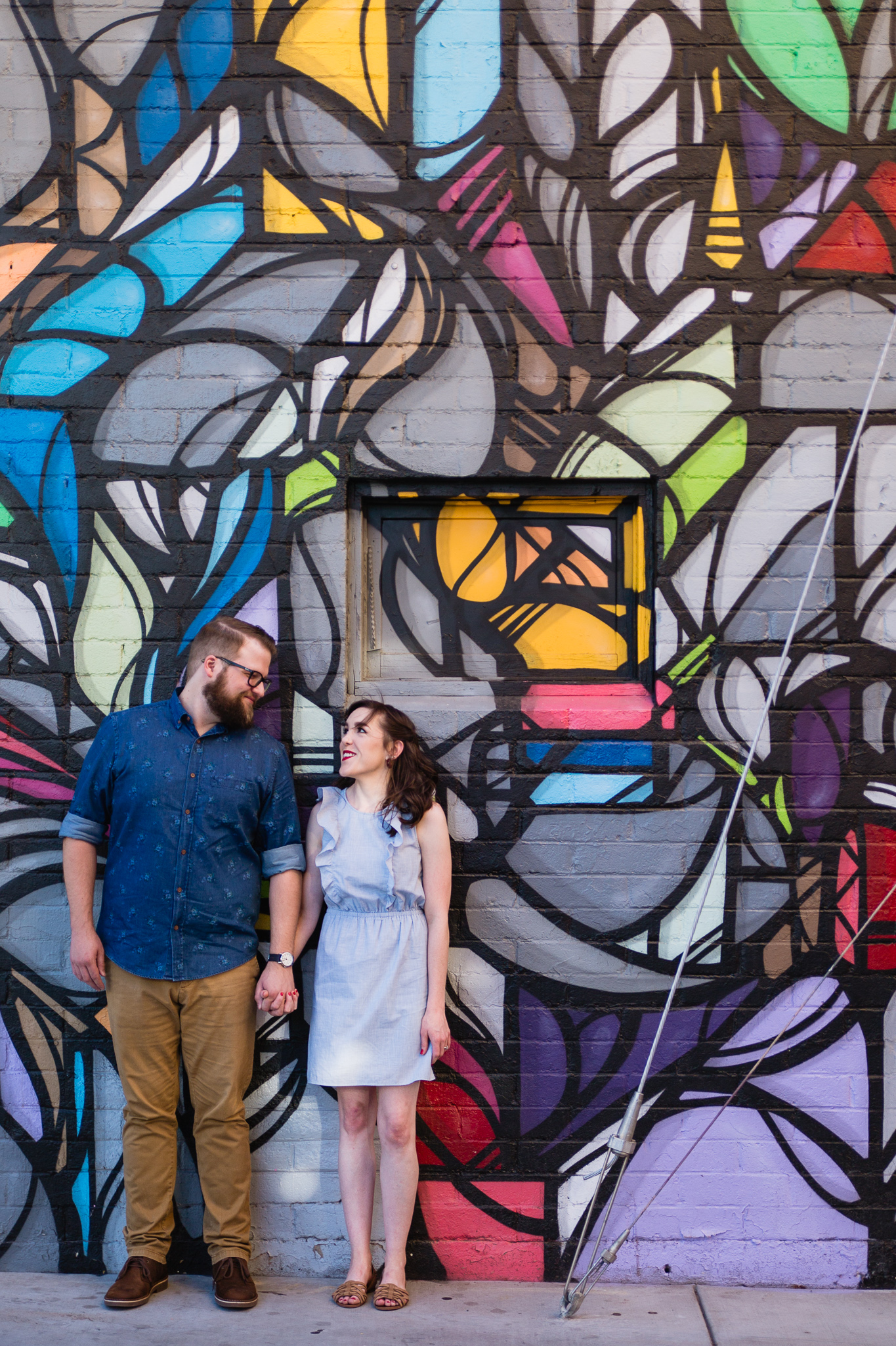 Couple posing in front of art mural during their urban engagement session by Phoenix engagement photographer PMA Photography.
