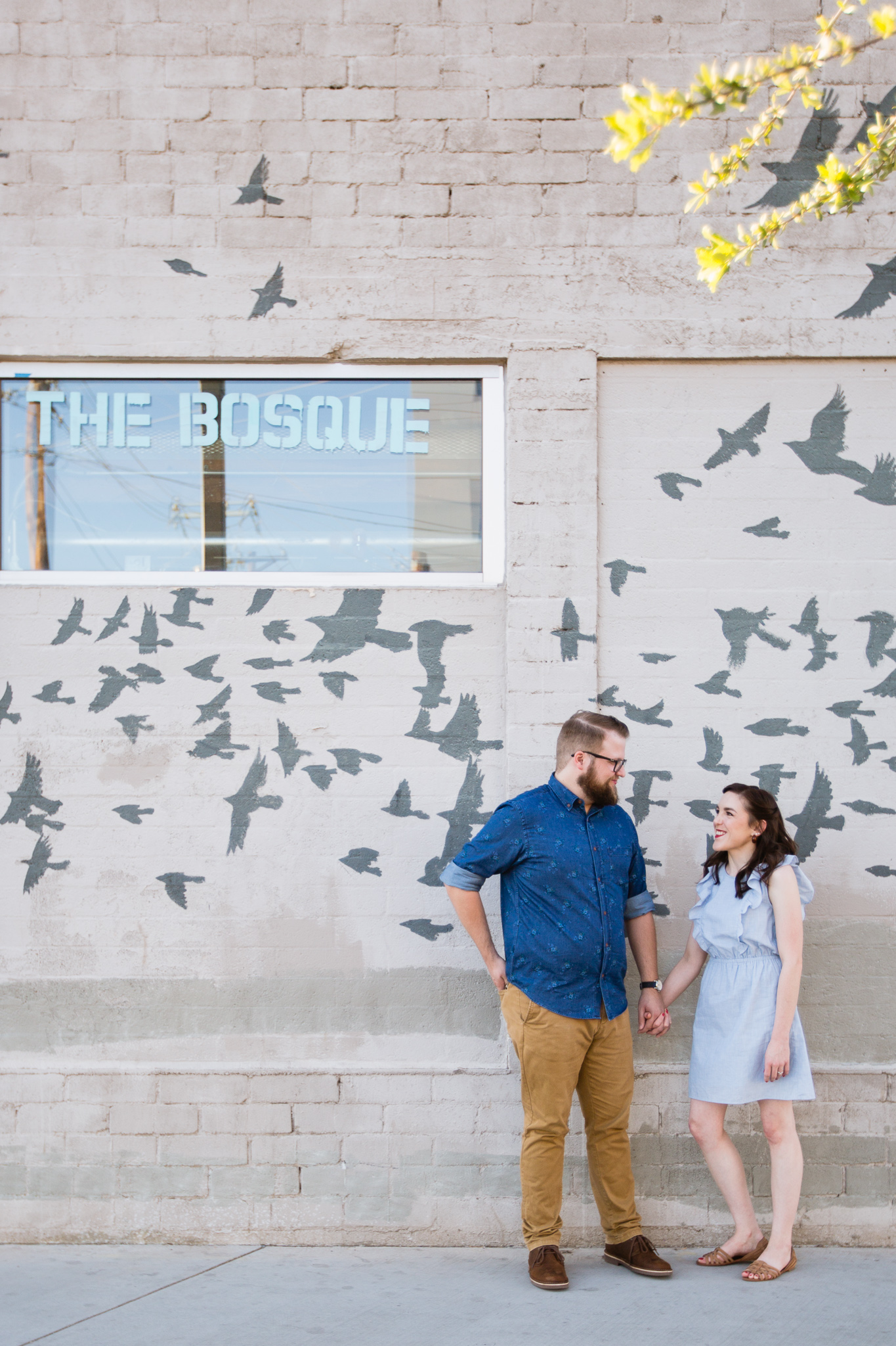 Couple looking at each other in front of a bird mural at Roosevelt Row during their downtown Phoenix engagement session by PMA Photography.