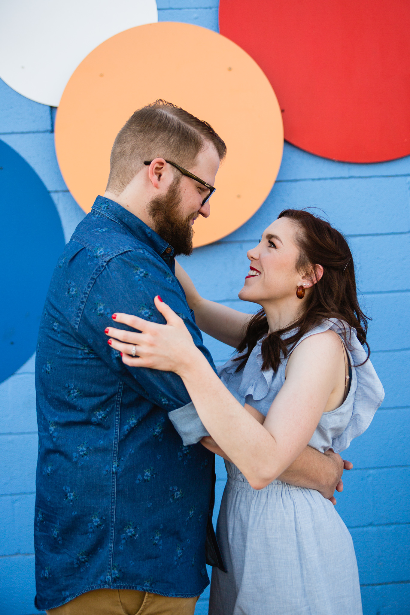 Couple looking at each other in front of colorful background at their engagement session by PMA Photography.