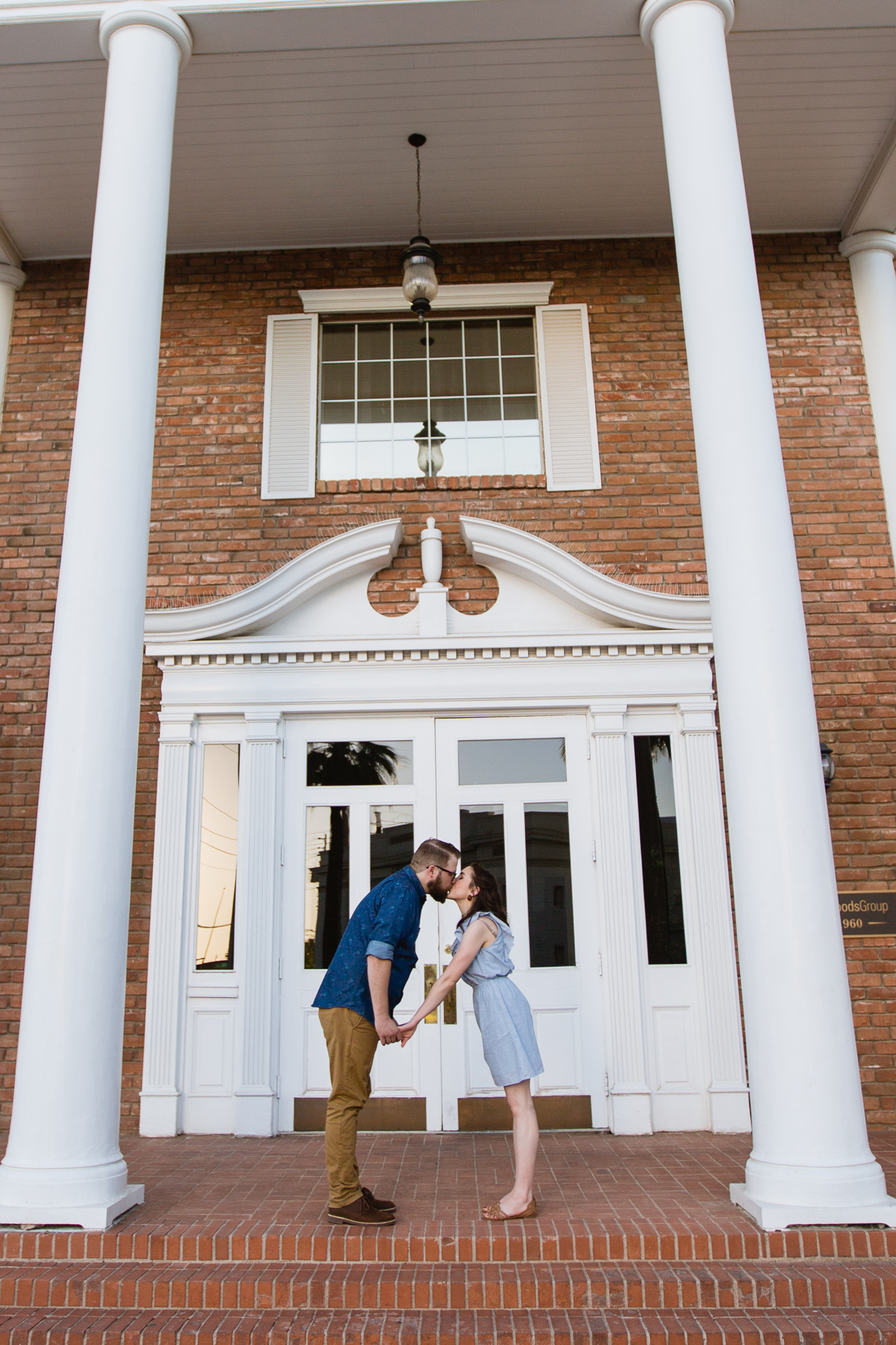 Couple kissing in front of old vintage brick building during their downtown engagement session by PMA Photography.