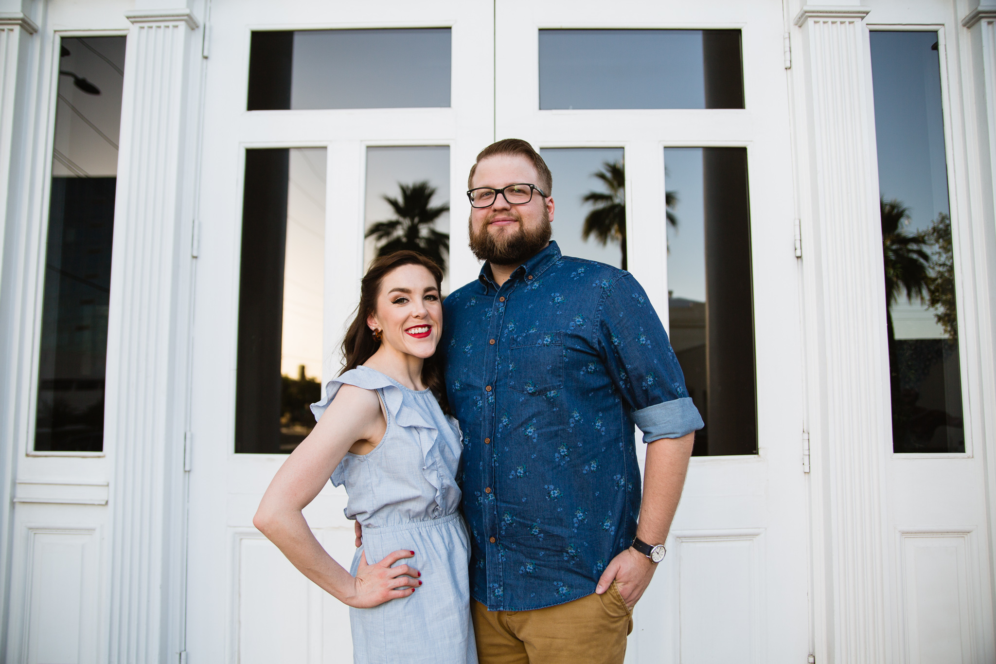 Couple posing in front of vintage white doors as the sun sets by Arizona engagement photographer by PMA Photography.