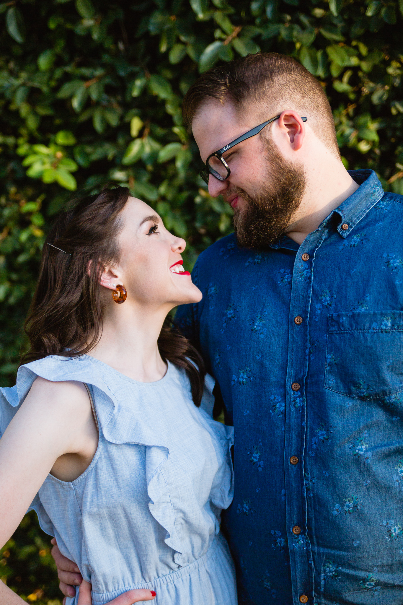 Couple looking at each other in front of a green wall during their downtown engagement session by Phoenix engagement photographer PMA Photography.