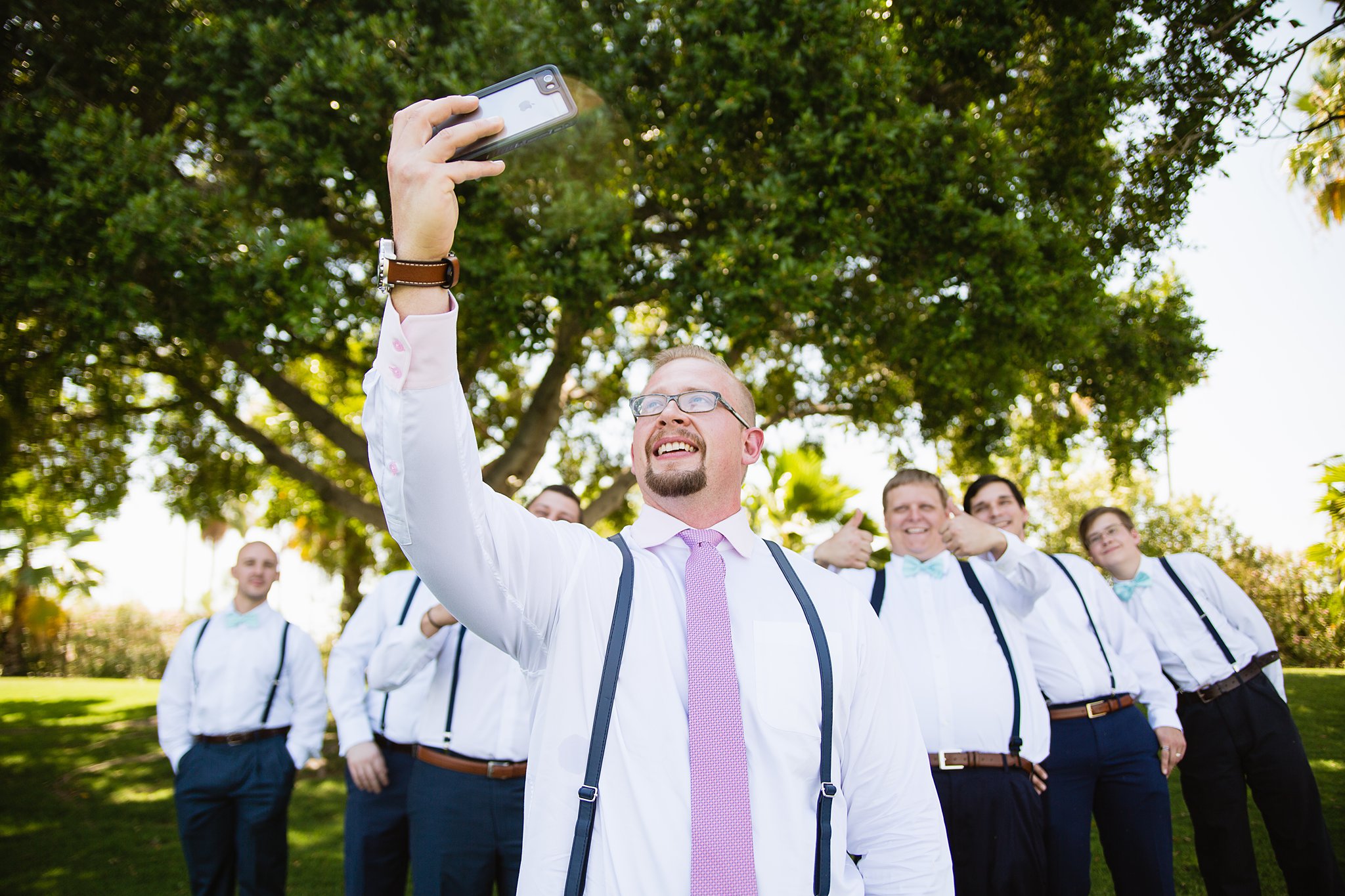 Groom and groomsmen taking a selfie together at a Val Vista Lakes wedding by Arizona wedding photographer PMA Photography.