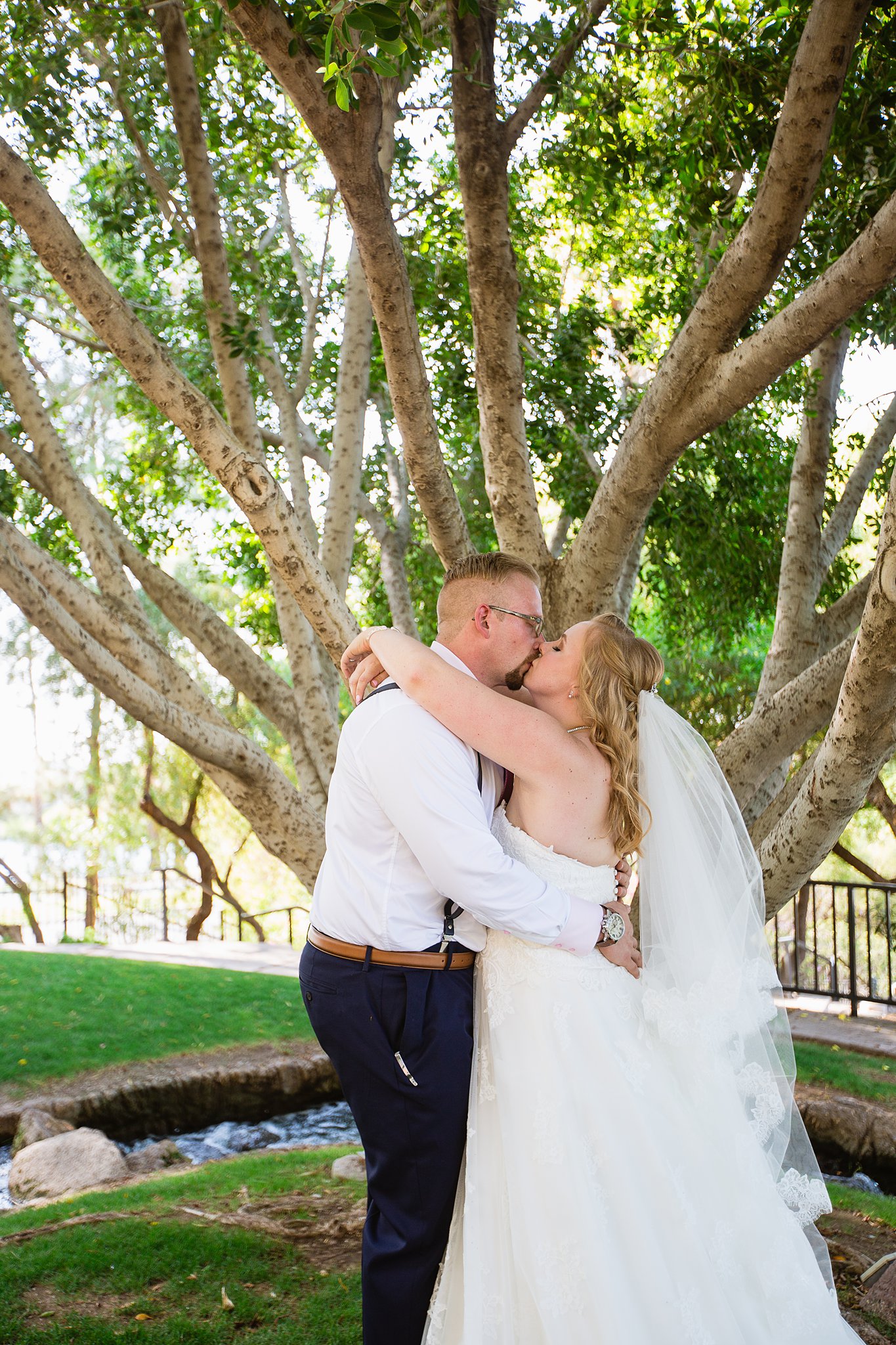 Bride and groom share a kiss during their Val Vista Lakes wedding by Arizona wedding photographer PMA Photography.