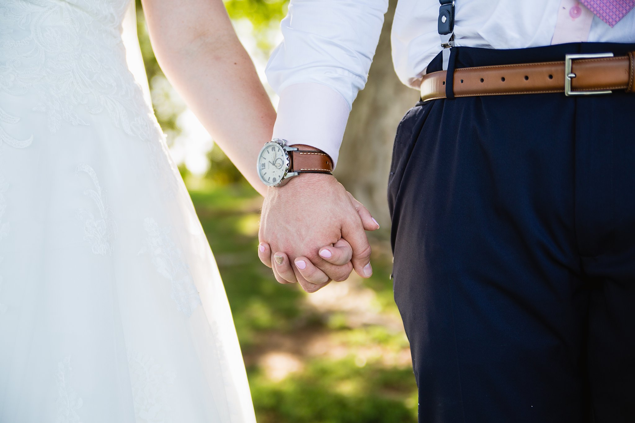 Close up image of bride and groom holding hands by PMA Photography.