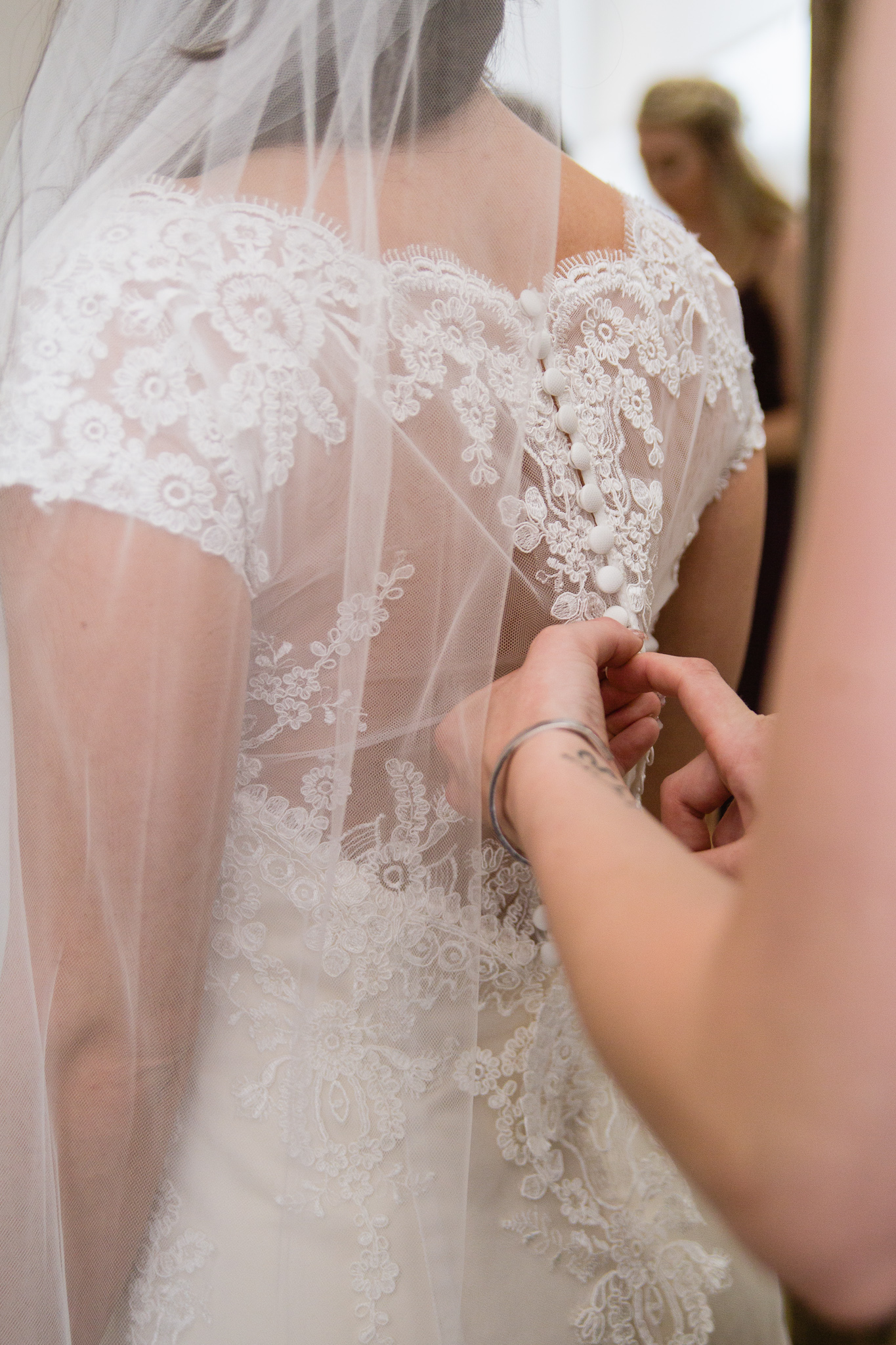 Bride's mother buttoning up her dress while getting ready for her wedding by Arizona wedding photographer PMA Photography.