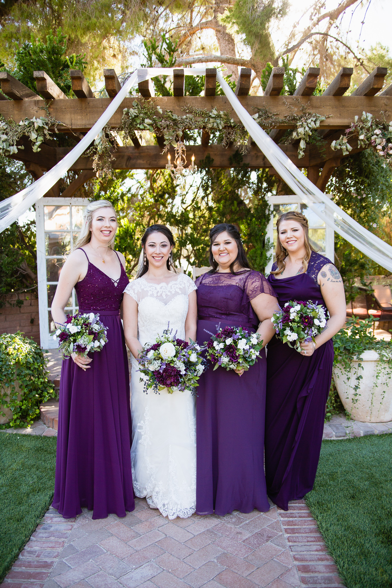 Bride with bridesmaids in purple mismatched bridesmaids dresses by Arizona wedding photographer PMA Photography.