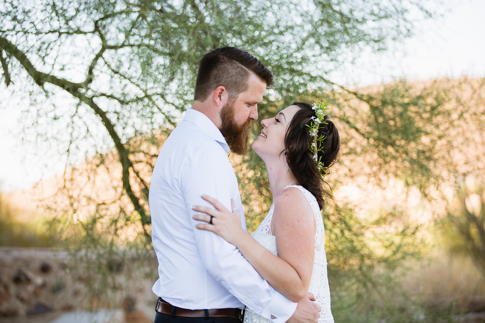 Bride and groom smile at each other in the desert by Arizona wedding photographer PMA Photography.