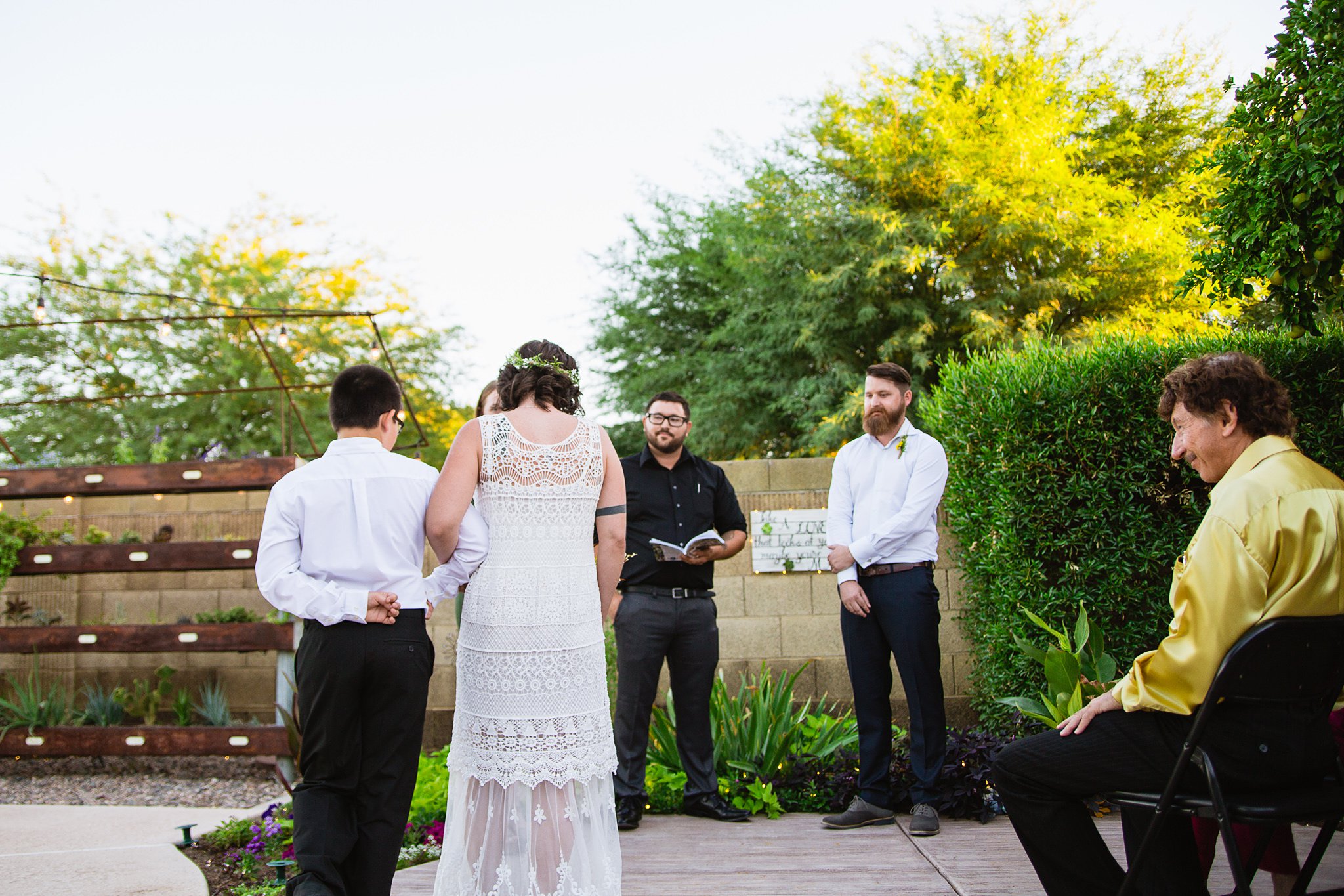 Bride being walked down the aisle by her son at her Arizona backyard garden wedding by Phoenix wedding photographer PMA Photography.