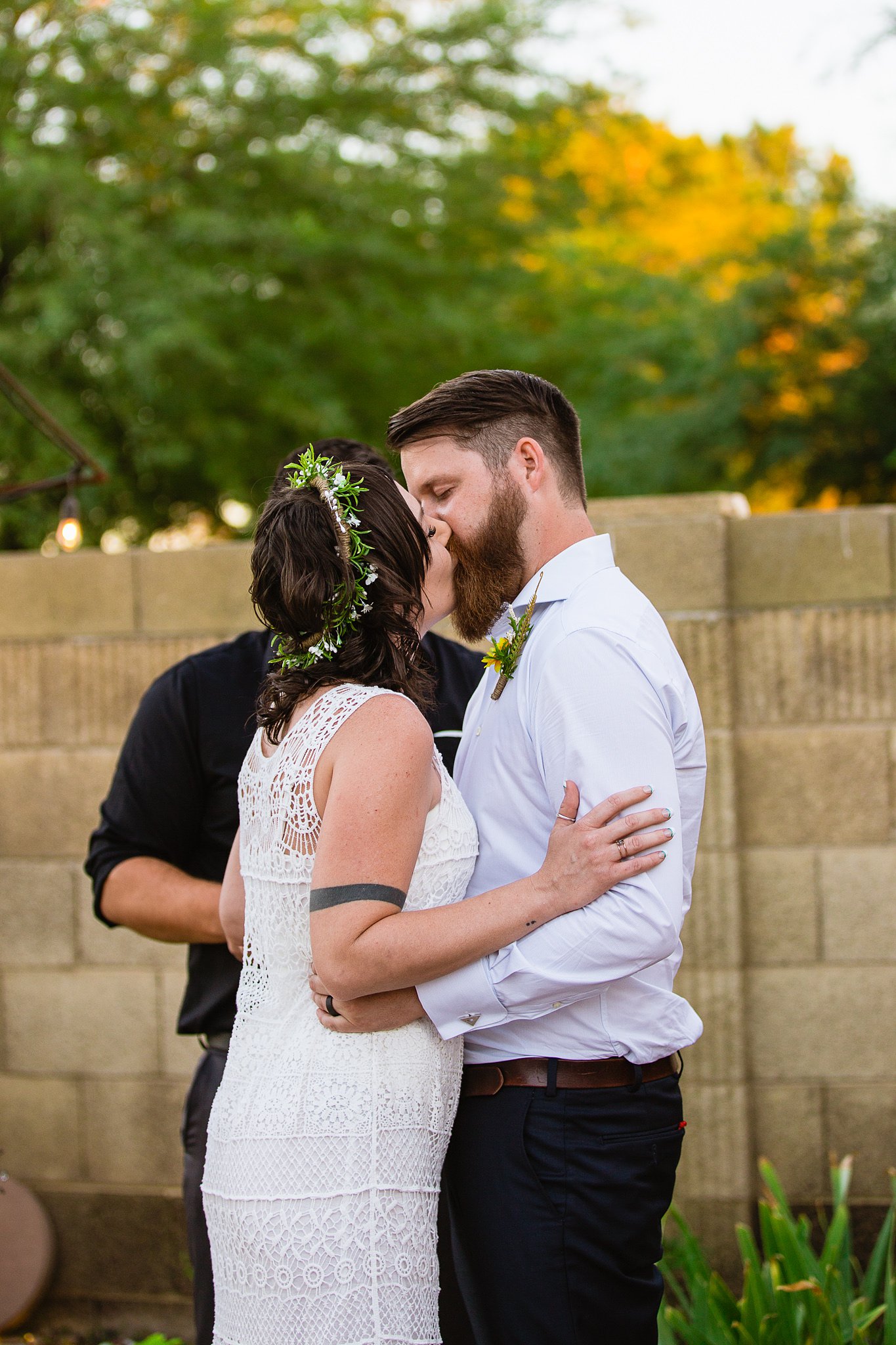 Bride and groom share their first kiss at their backyard garden wedding ceremony by PMA Photography.