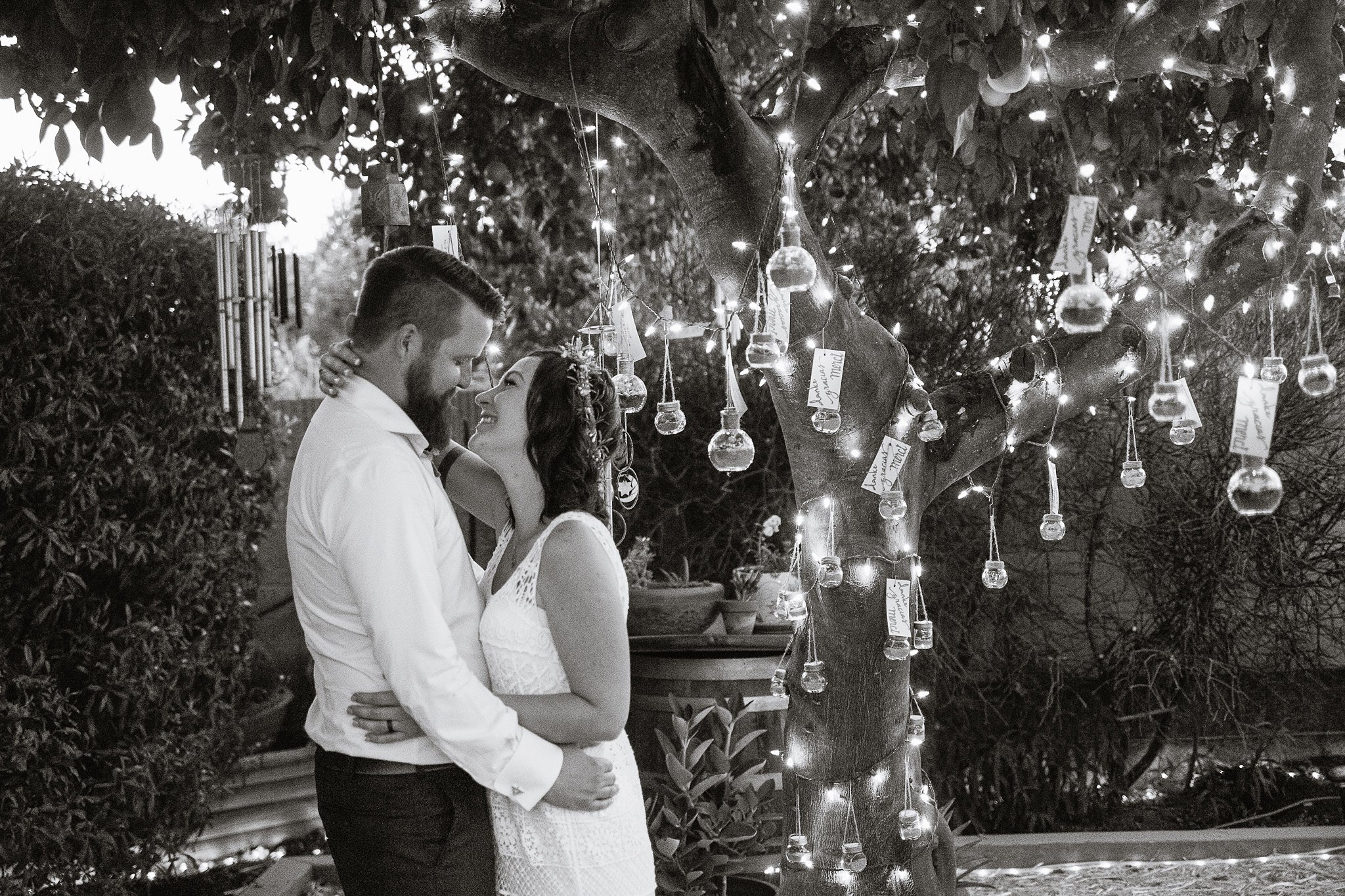Black and white photo of bride and groom in front of lit favor tree by Phoenix wedding photographer PMA Photography