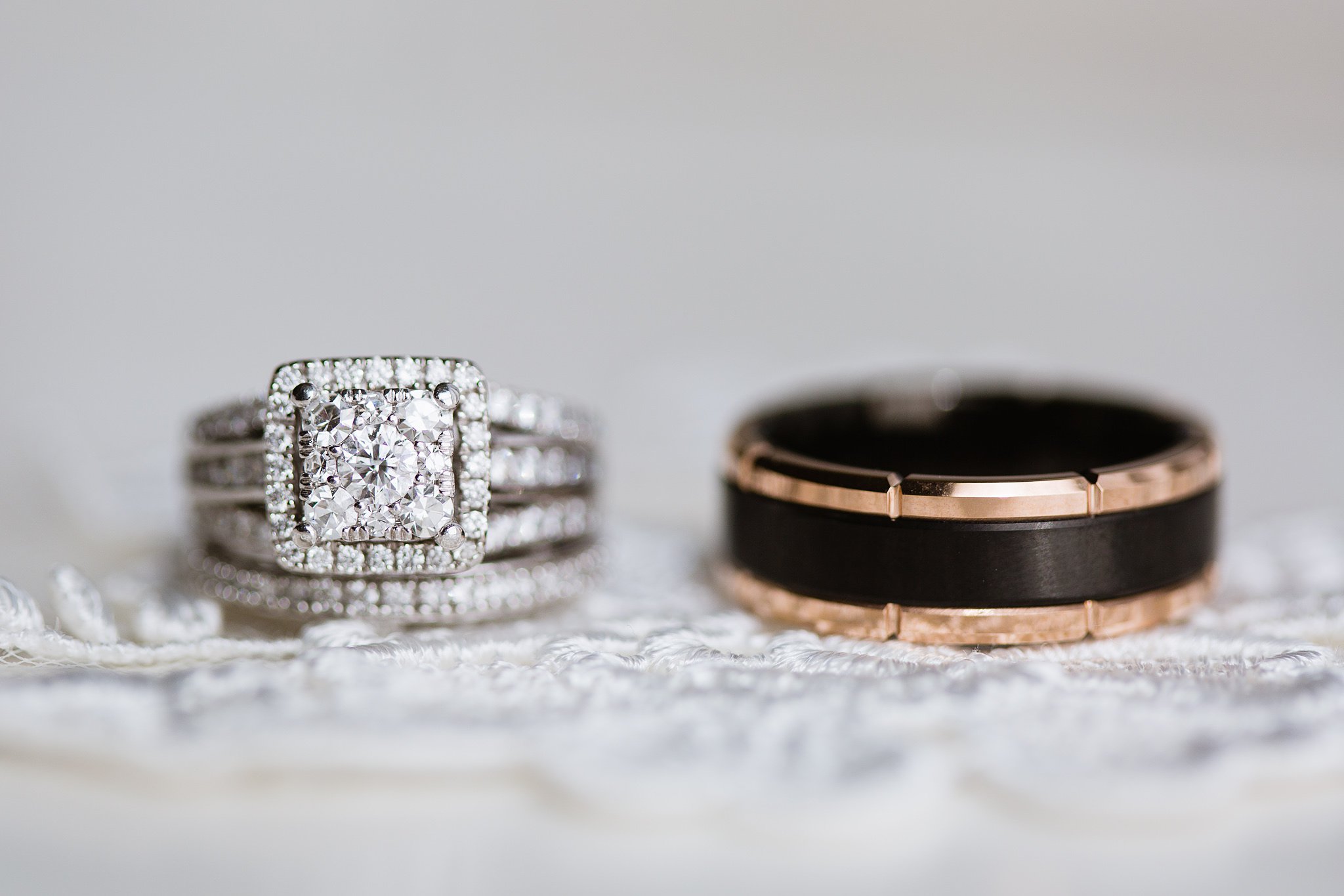 Close up images of bride's square white gold and diamond wedding ring and groom's black and gold wedding band.
