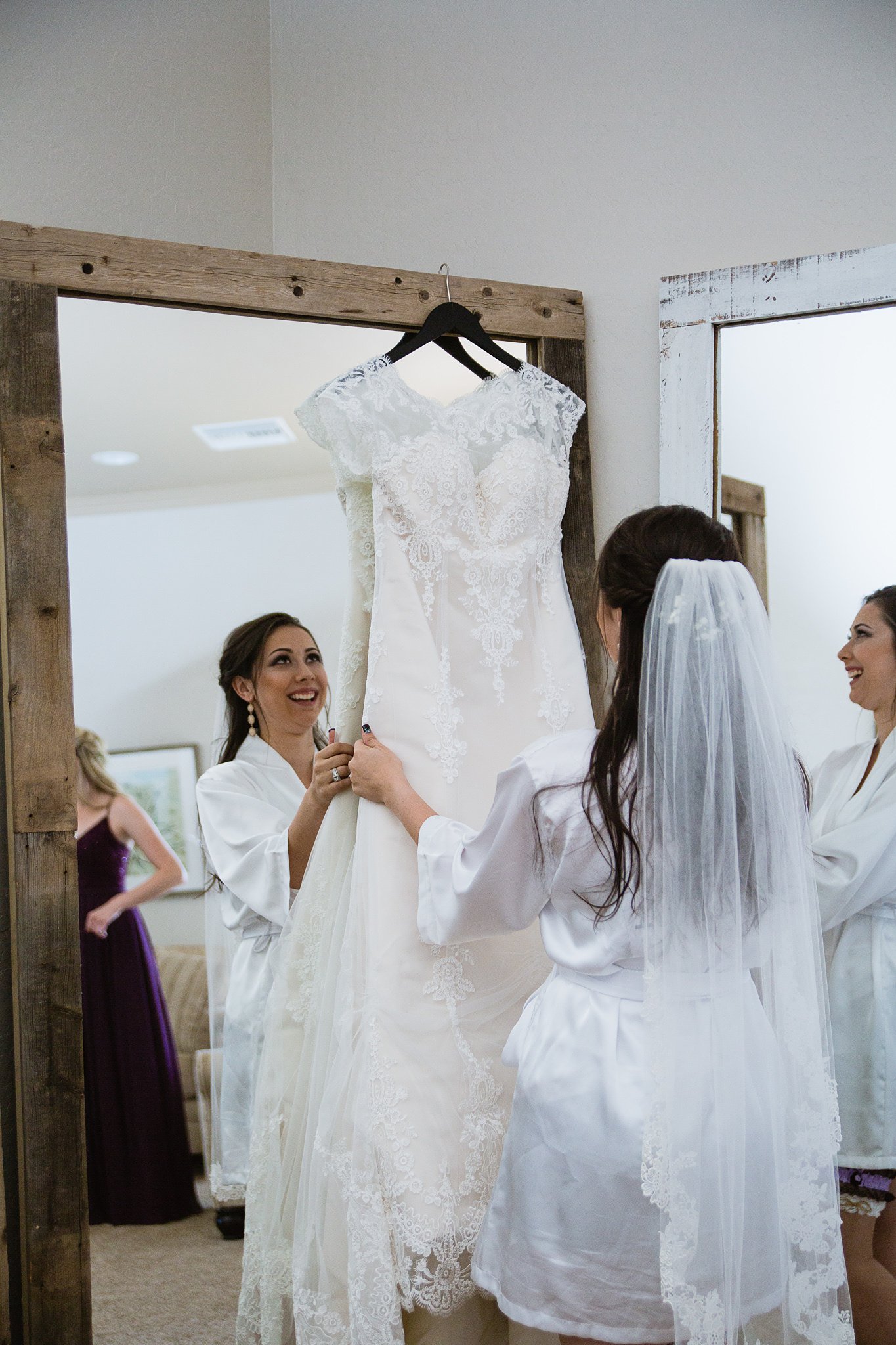 Bride looking at her wedding dress while getting ready in the Schnepf Farms Farmhouse by Arizona Wedding Photographer PMA Photography.