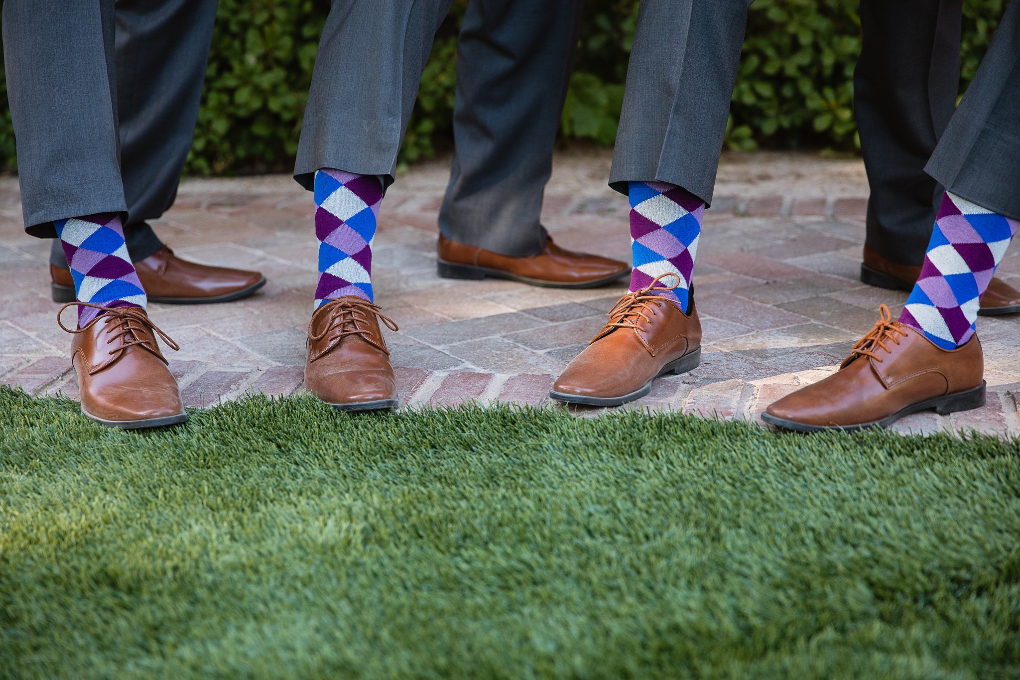 Groomsmen purple and grey colored socks in brown dress shoes by wedding photographer PMA Photography.