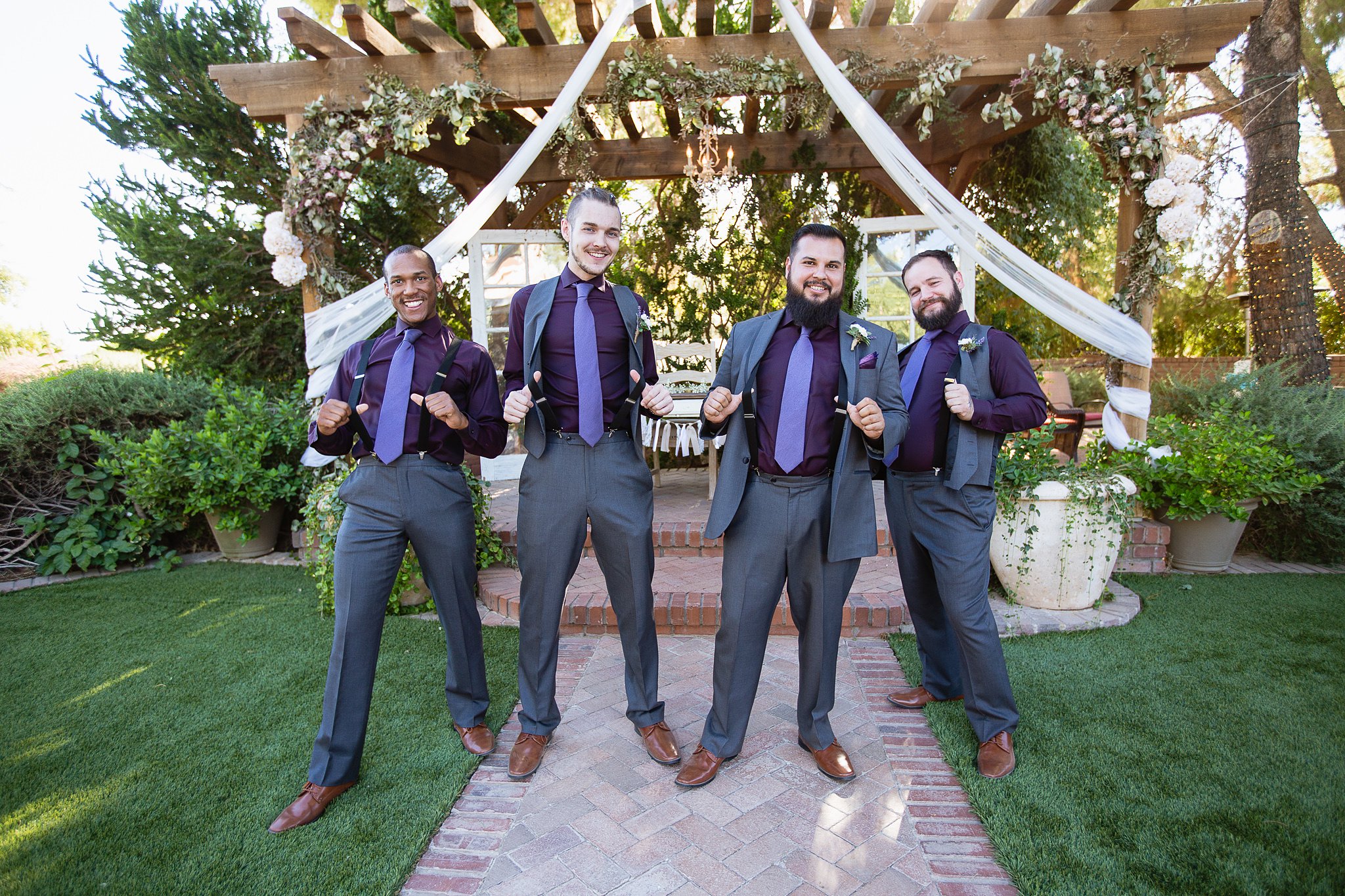 Groomsmen showing off the suspenders in their Purple and grey outfits at Schnepf Farms by Arizona wedding photographer PMA Photography.