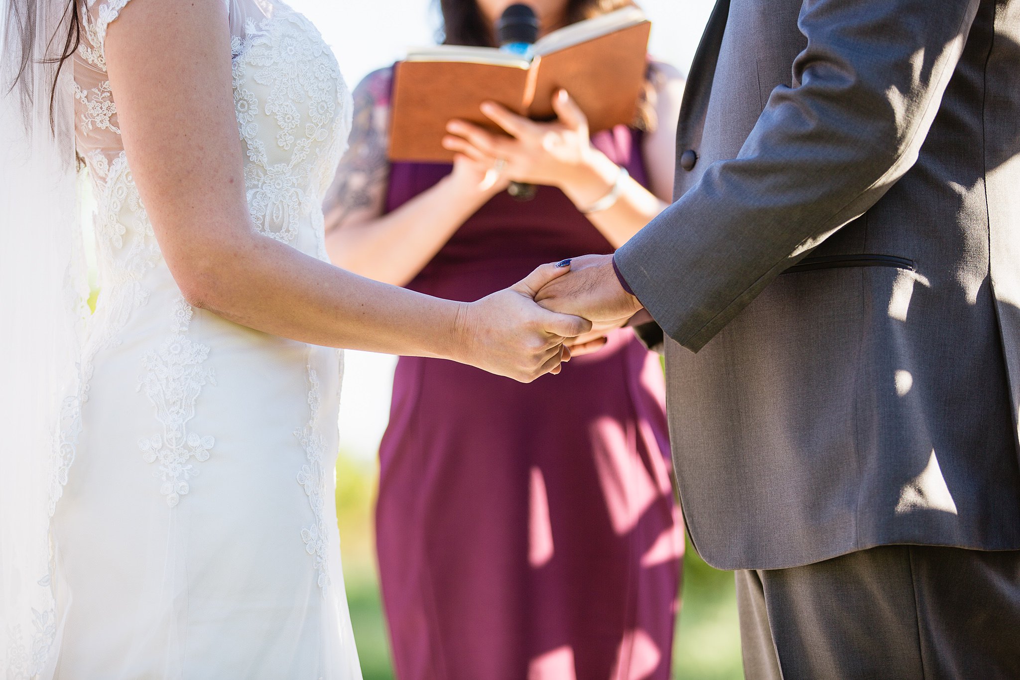 Close up image of bride and groom holding hands during a special hand reading at their Wedding ceremony at the Schnepf Farm's Farmhouse by Arizona wedding photographer PMA Photography.