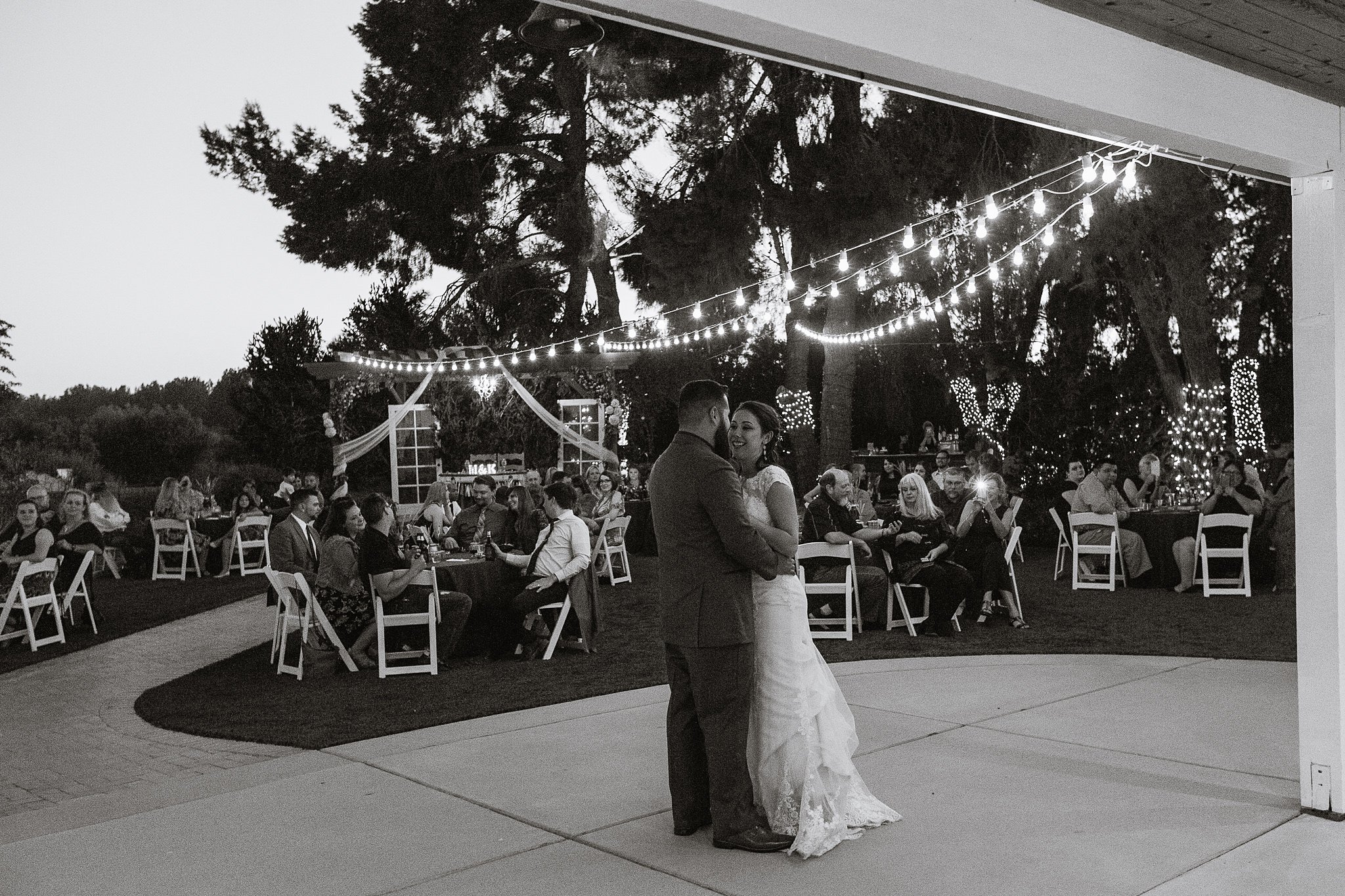 Black and white image of bride and groom's first dance at their Schnepf Farms Farmhouse wedding reception by Arizona wedding photographer PMA Photography.