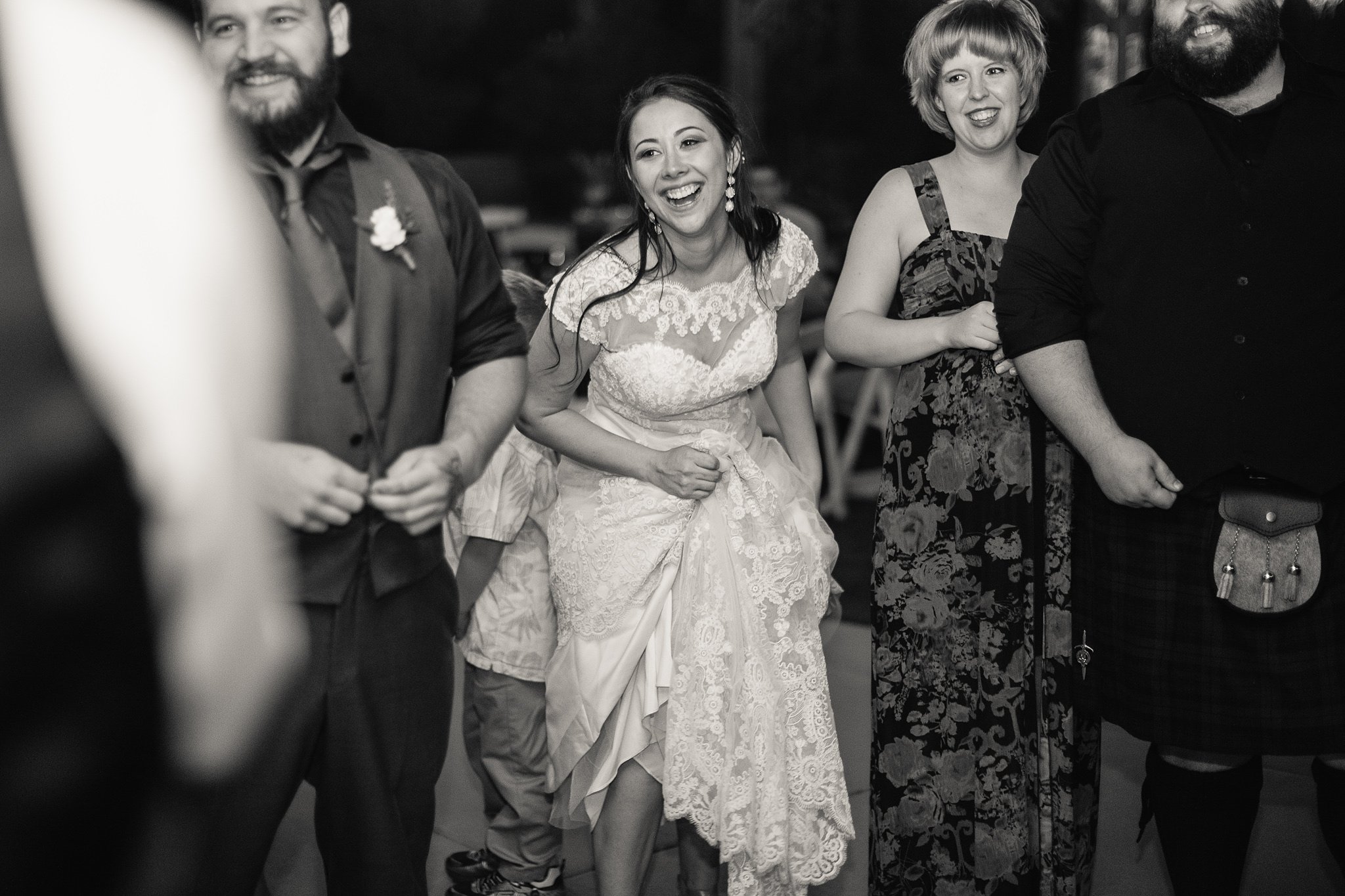 Black and white image of bride having fun dancing with guests at wedding reception by Arizona wedding photographer PMA Photography.