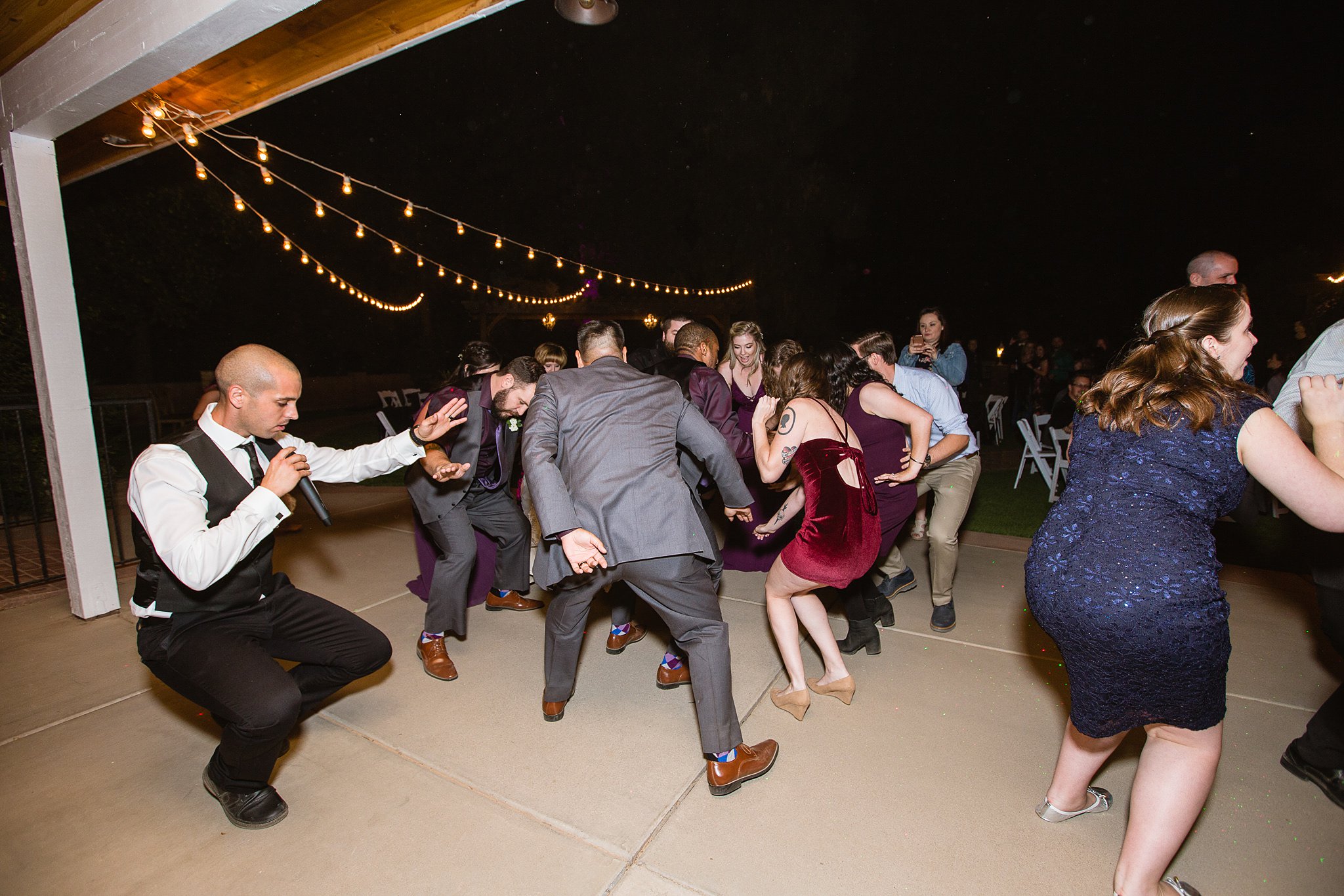 RJ of East Coast DJs leading the wedding reception guests in a dance at Schnepf Farms Farmhouse by Arizona wedding photographer PMA Photography.