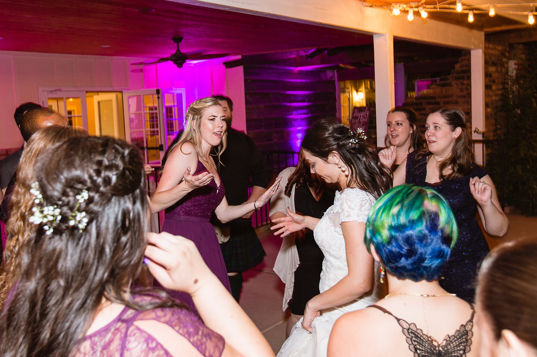 Bride and bridesmaid having fun dancing with guests at wedding reception by Arizona wedding photographer PMA Photography.