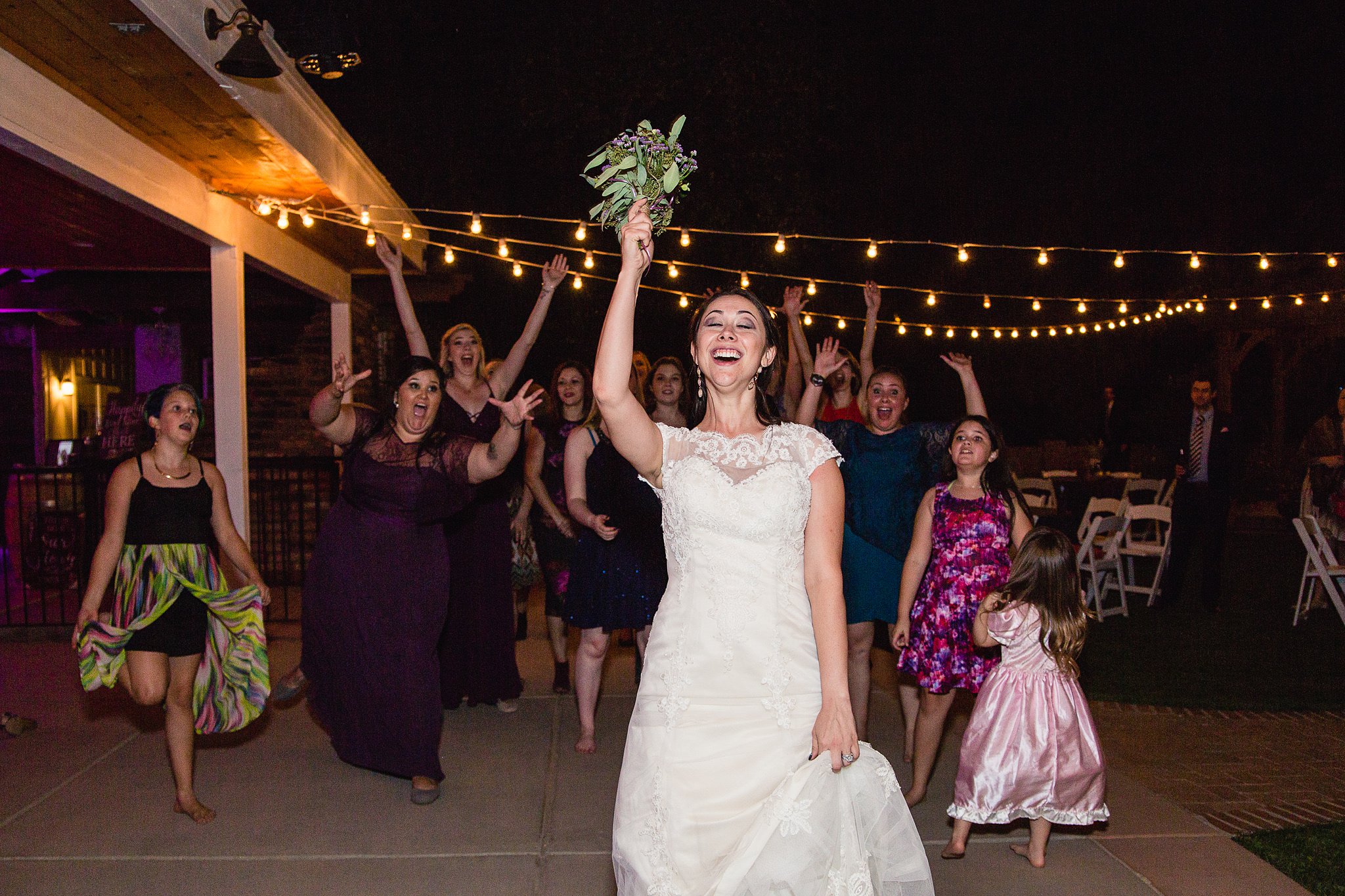 Bride tossing the bouquet to guests by Arizona wedding photographer PMA Photography.