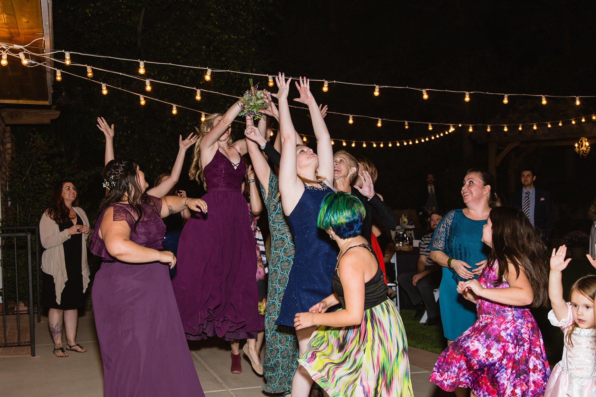 Guests catching bouquet at wedding reception by wedding photographer PMA Photography.