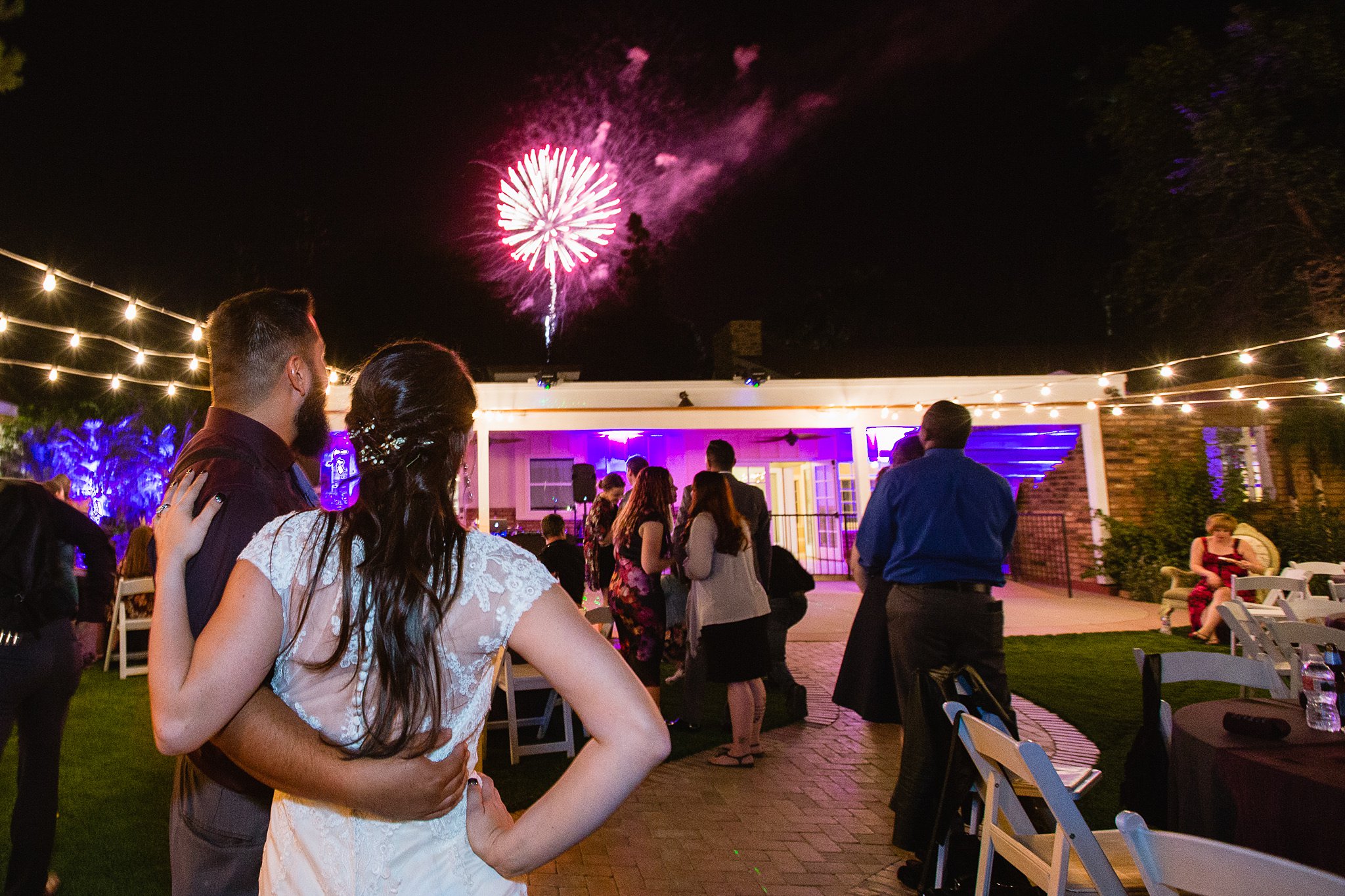 Bride and groom watch fireworks with guests at their wedding reception at Schnepf Farms by Phoenix wedding photographer PMA Photography.