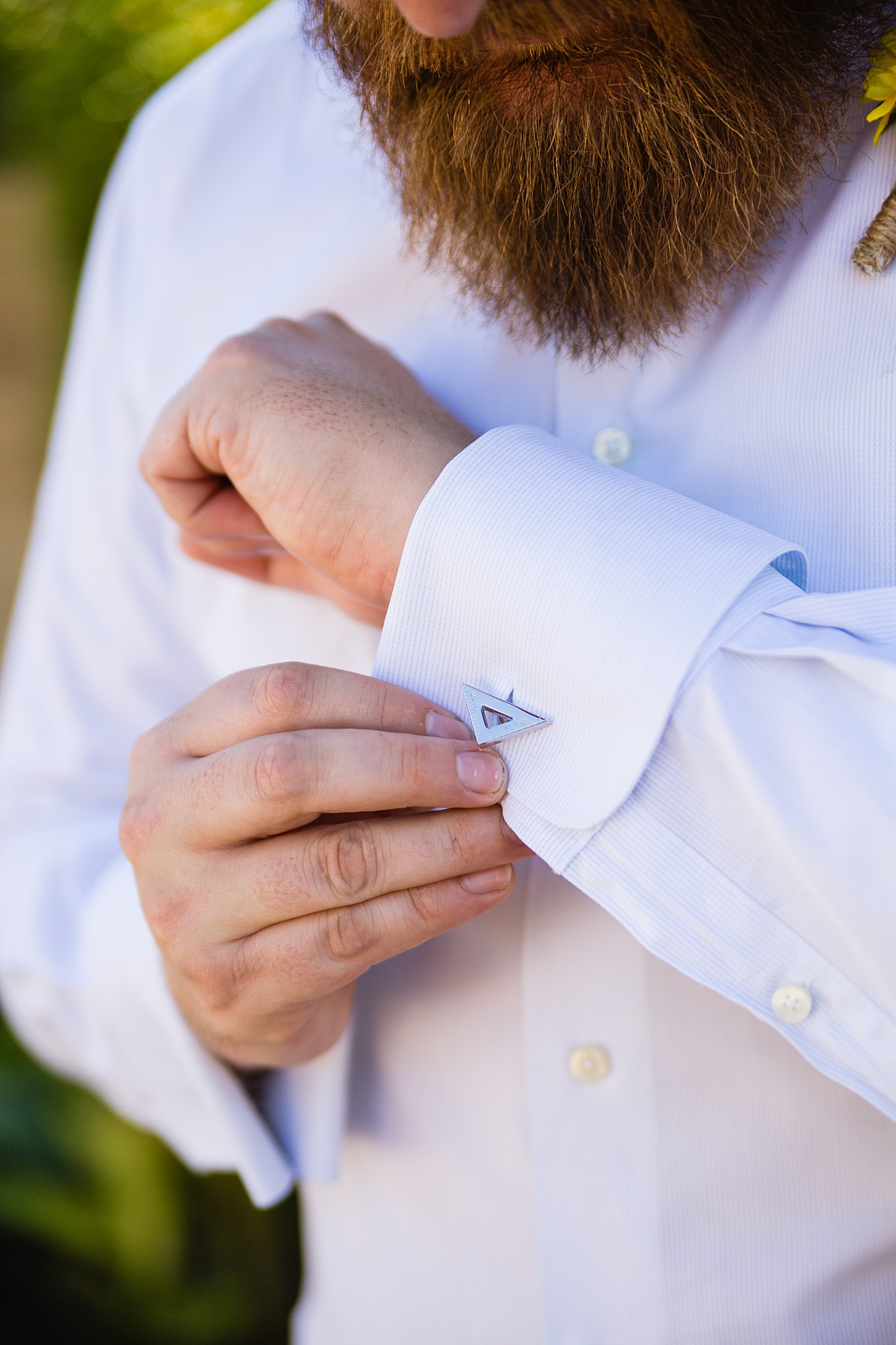 Close up image of the groom adjusting his custom cuff link by Arizona wedding photographer PMA Photography.