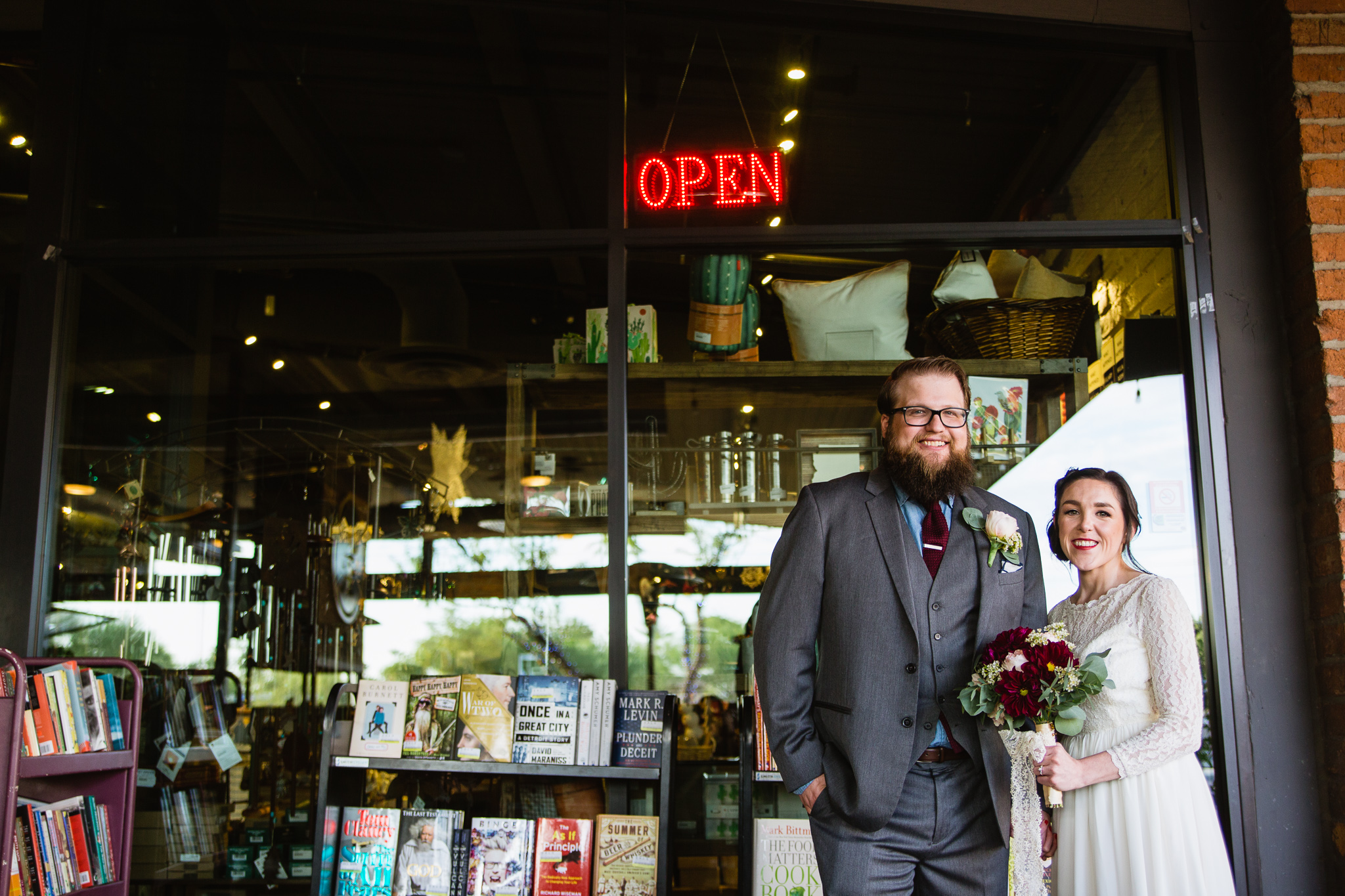 Vintage inspired bride and groom in front of the open sign at Changing Hands bookstore at their book themed wedding in downtown Phoenix.