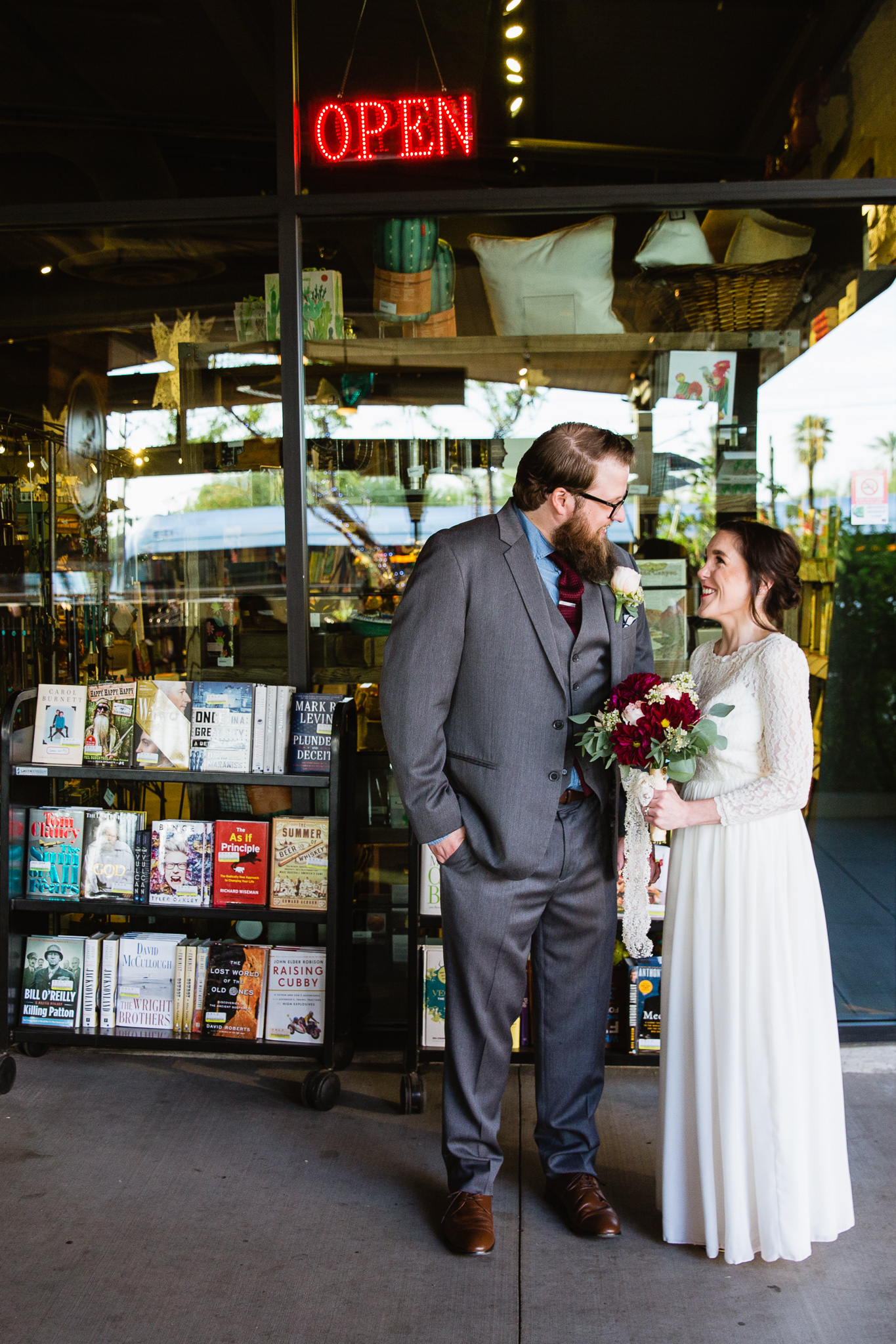 Vintage inspired bride and groom in front of the open sign at Changing Hands bookstore at their book themed wedding in downtown Phoenix.