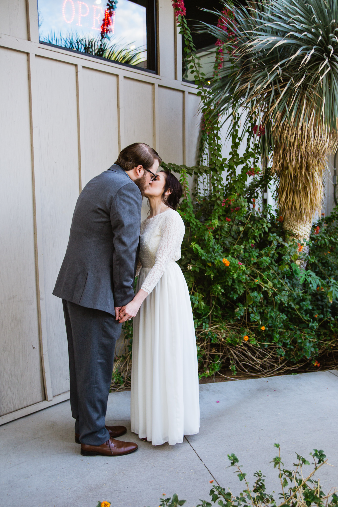 Vintage bride and groom kissing in front of Changing Hand bookstore in Phoenix Arizona.