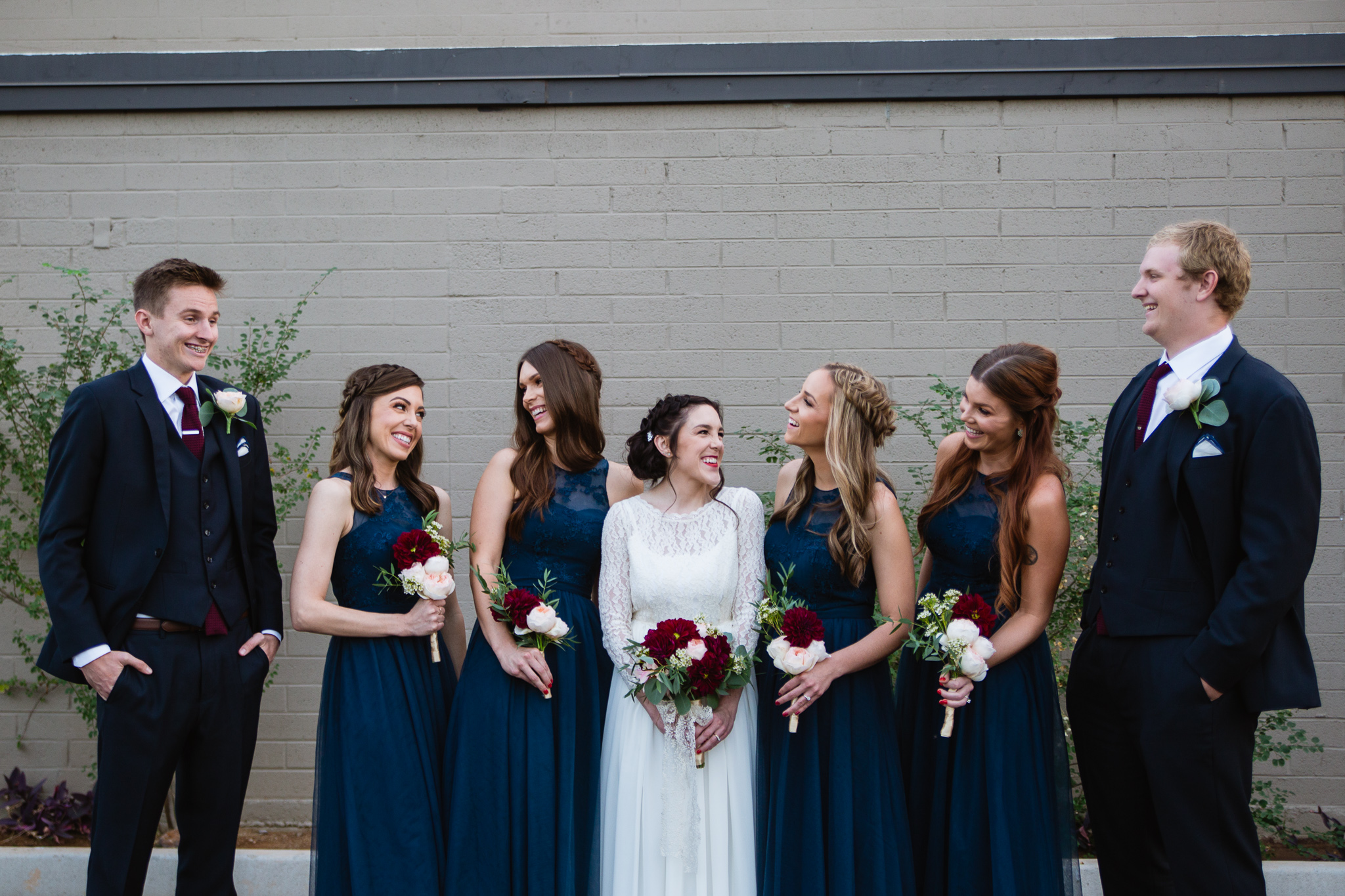 Candid moment with a vintage themed maroon and navy bridal party. Bride with her mixed gender bridal party.