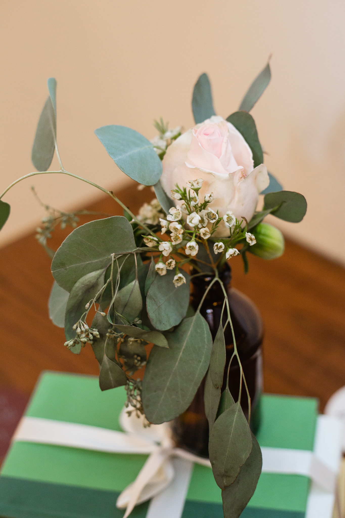 Vintage bottle with eucalyptus and rose and waxflower and vintage books centerpieces at an urban wedding reception.