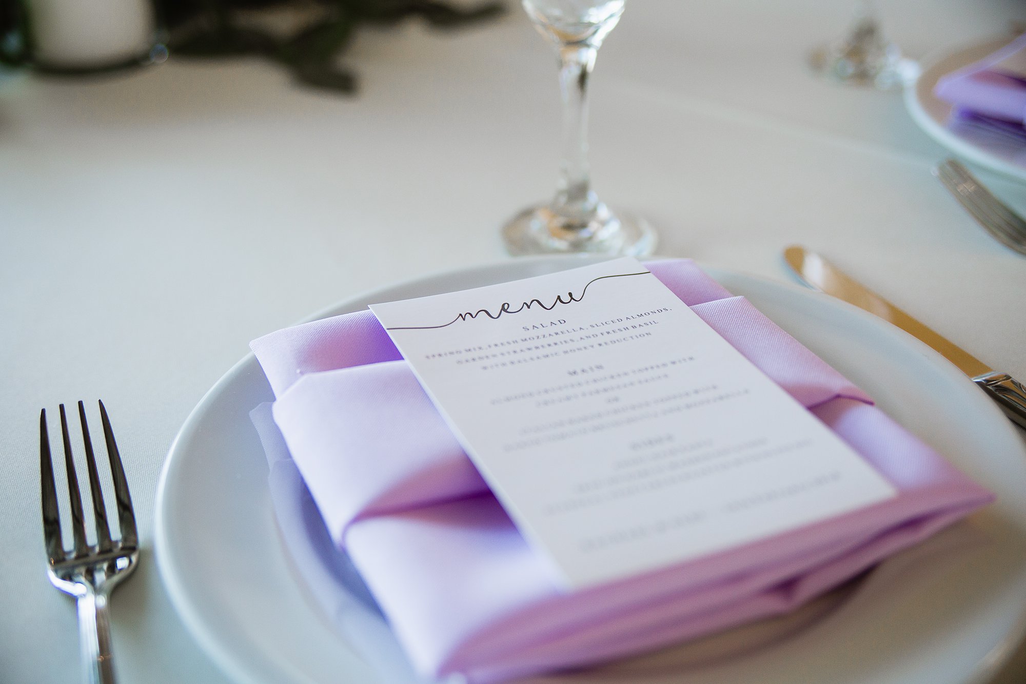 Wedding menu stationary piece on top of lavender napkin by wedding photographer PMA Photography.