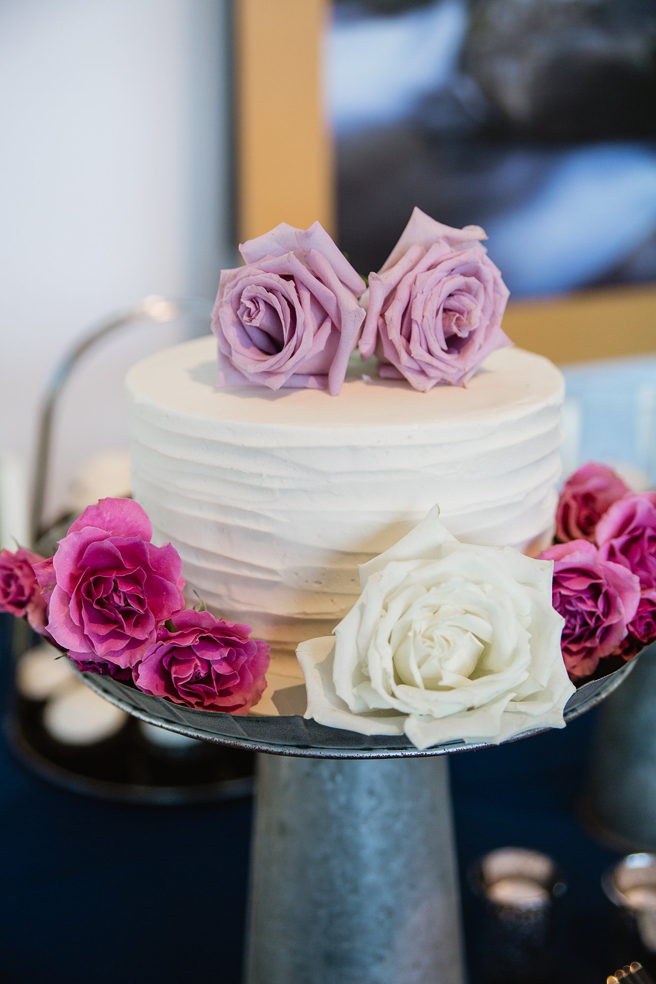 Simple white wedding cake topped with white lavender and pink roses.