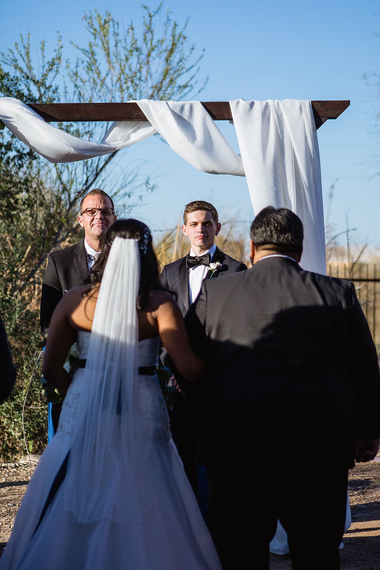 Groom watching bride's father walk her down the aisle during wedding ceremony at the Rio Salado Audubon by Phoenix wedding photographers PMA Photography.