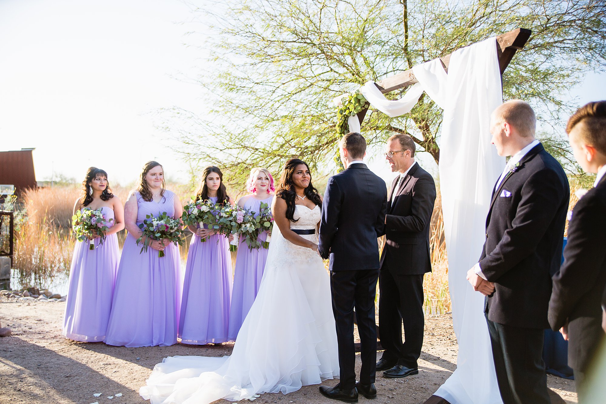 Bride and groom at the altar surrounded by bridesmaids and groomsmen during wedding ceremony at the Rio Salado Audubon by Phoenix wedding photographers PMA Photography.