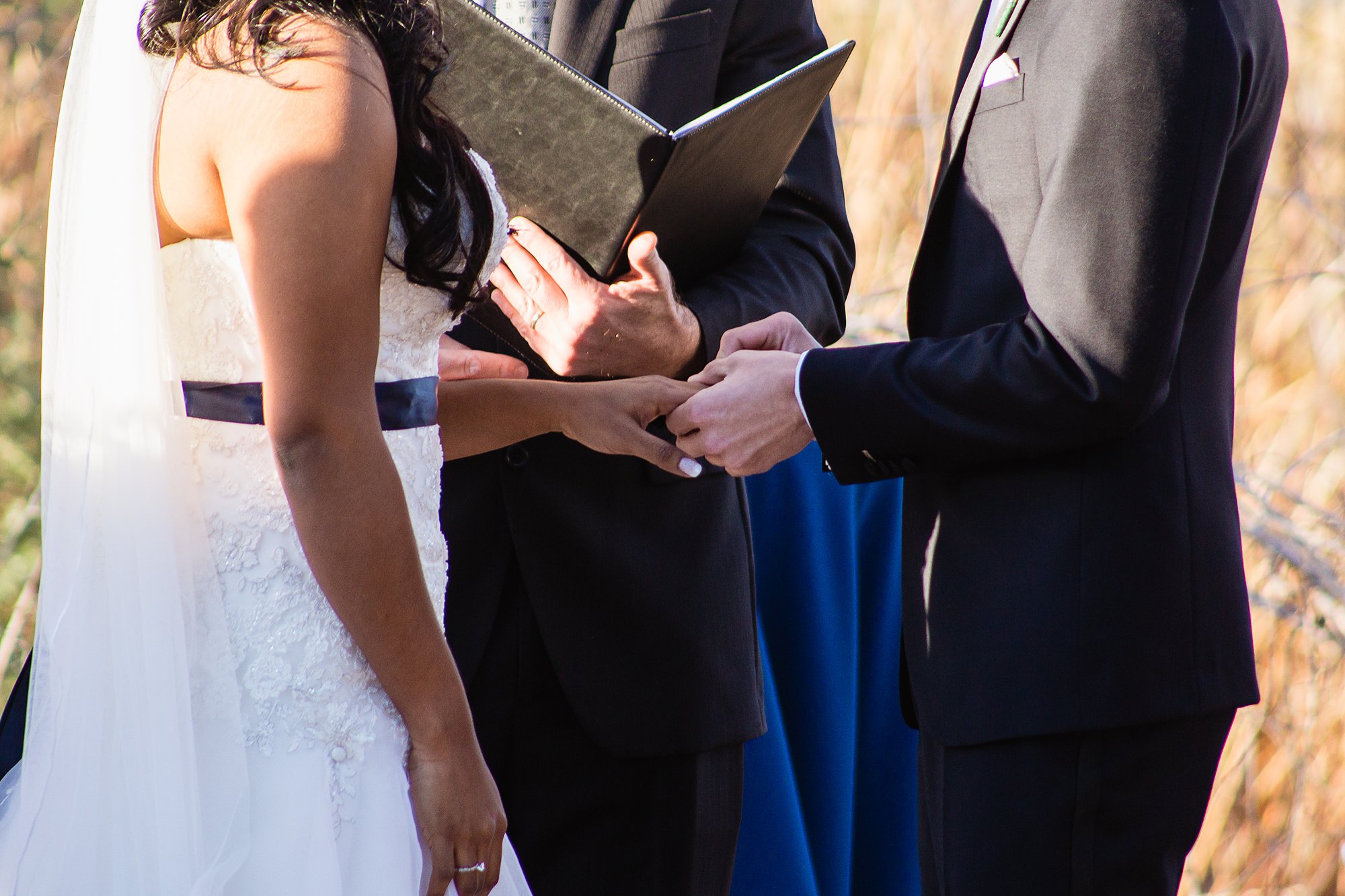 Groom placing ring on bride's finger during wedding ceremony at the Rio Salado Audubon by Phoenix wedding photographers PMA Photography.