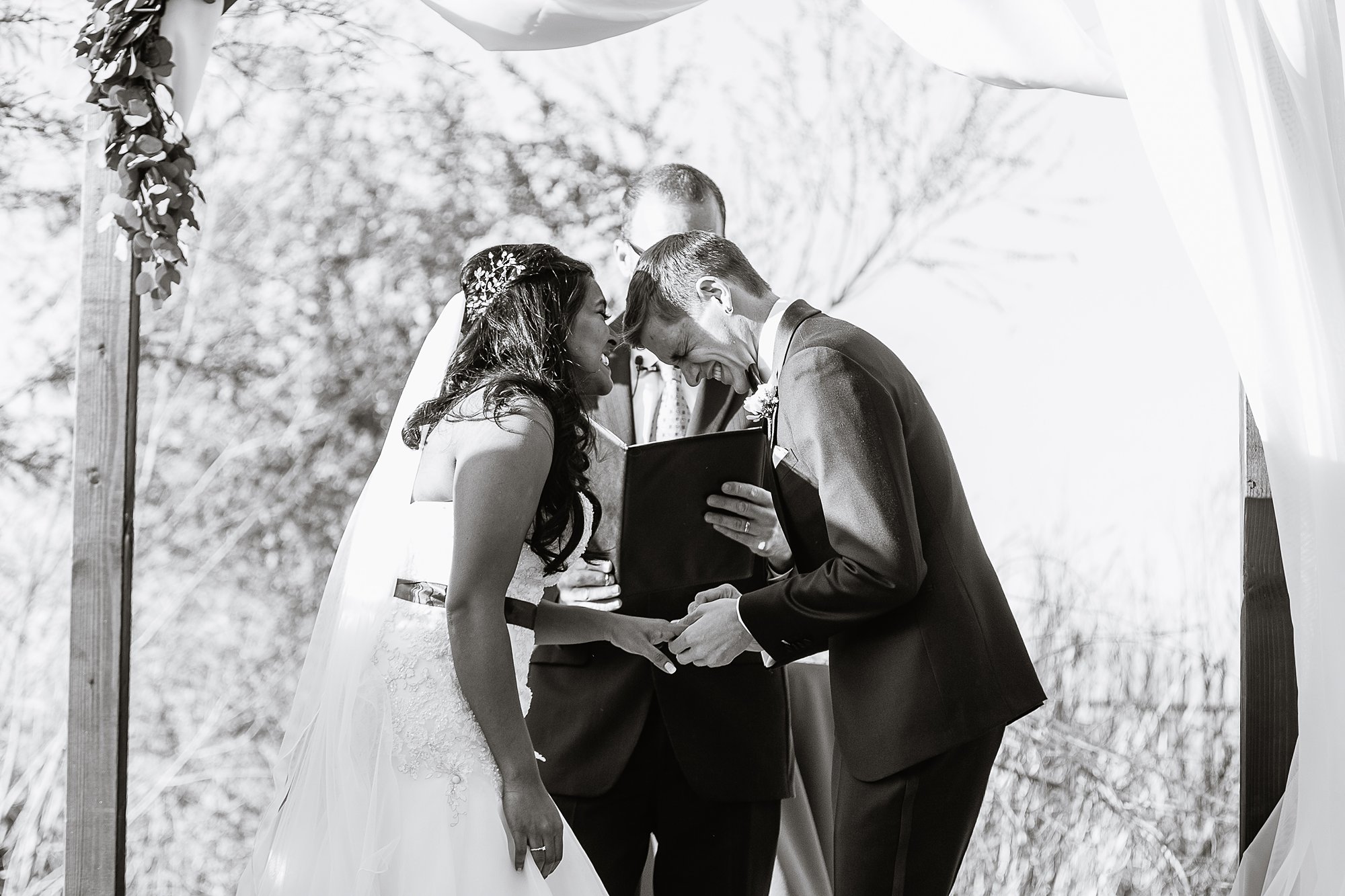 Black and white image of the bride and groom sharing a laugh during wedding ceremony at the Rio Salado Audubon by Phoenix wedding photographers PMA Photography.