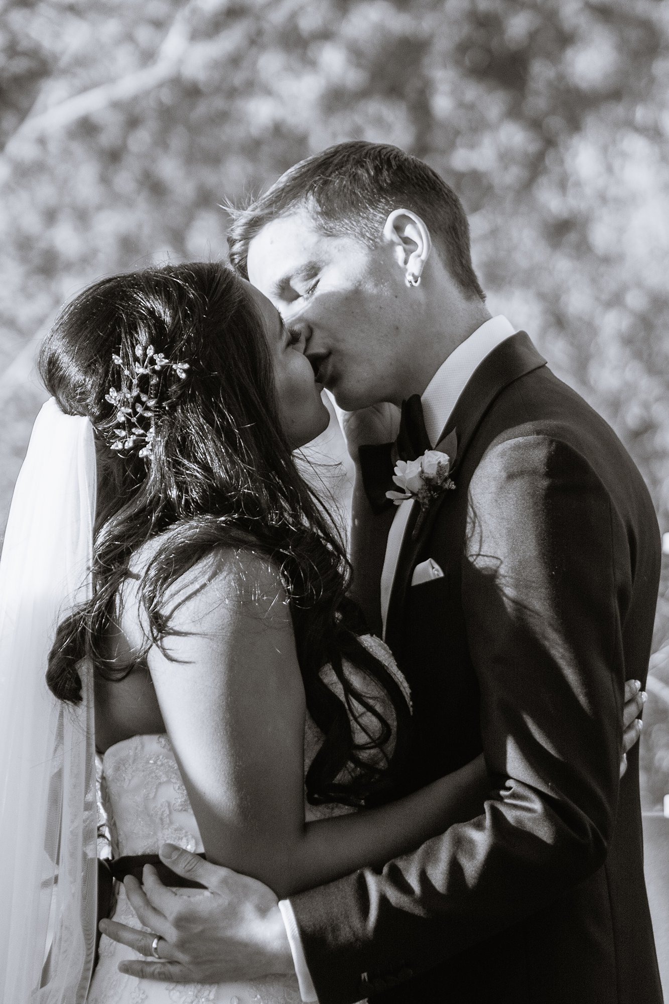 Black and white image of bride and groom sharing their first kiss as husband and wife during wedding ceremony at the Rio Salado Audubon by Phoenix wedding photographers PMA Photography.