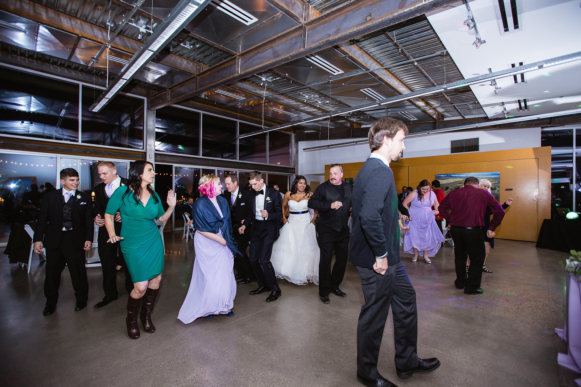 DJ leading the wedding guests in a line dance during the wedding reception at the Rio Salado Audubon center by Phoenix wedding photographer PMA Photography.