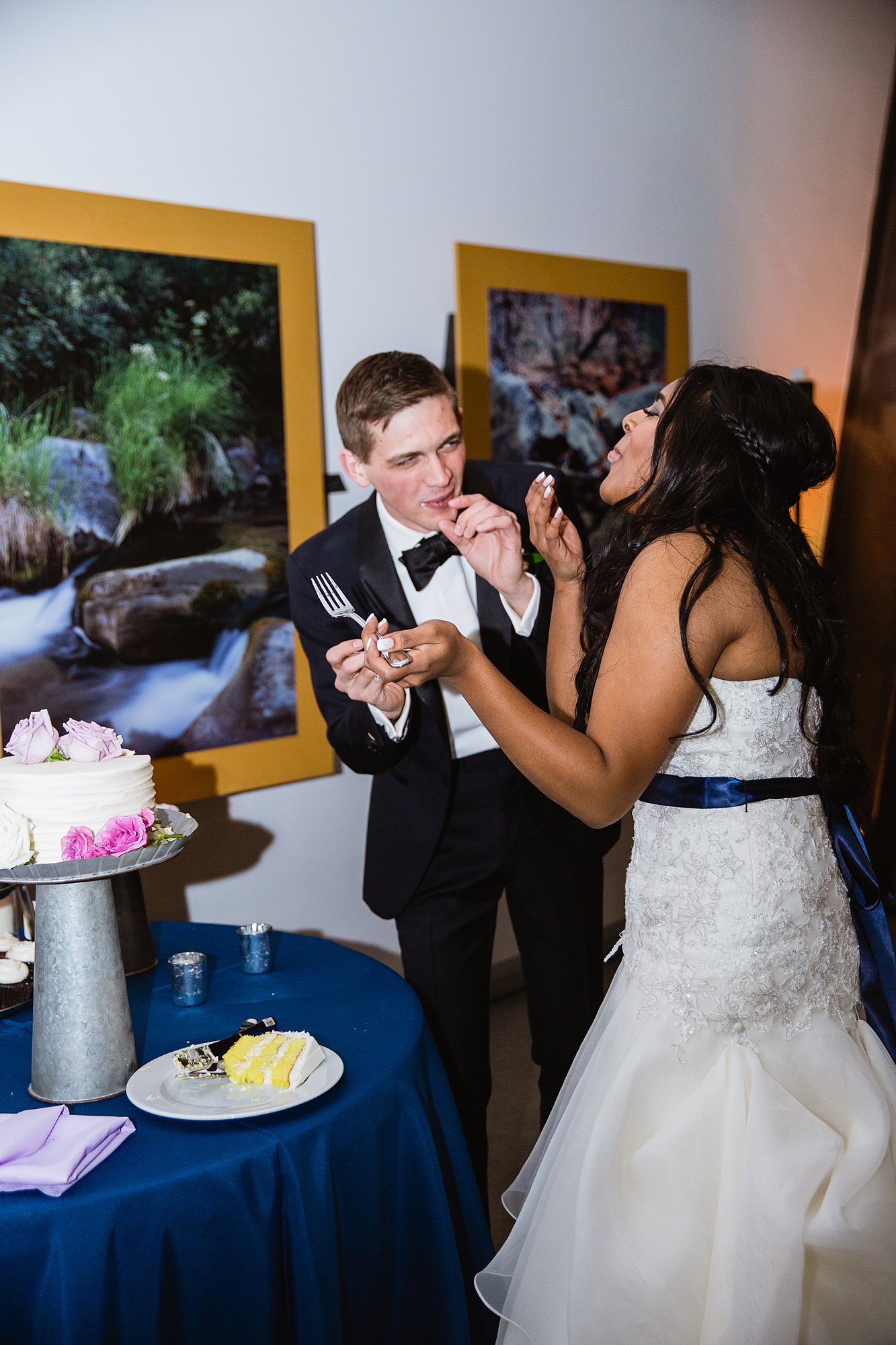 Bride and groom laughing after feeding each other cake at their reception at the Rio Salado Audubon center by Phoenix wedding photographer PMA Photography.