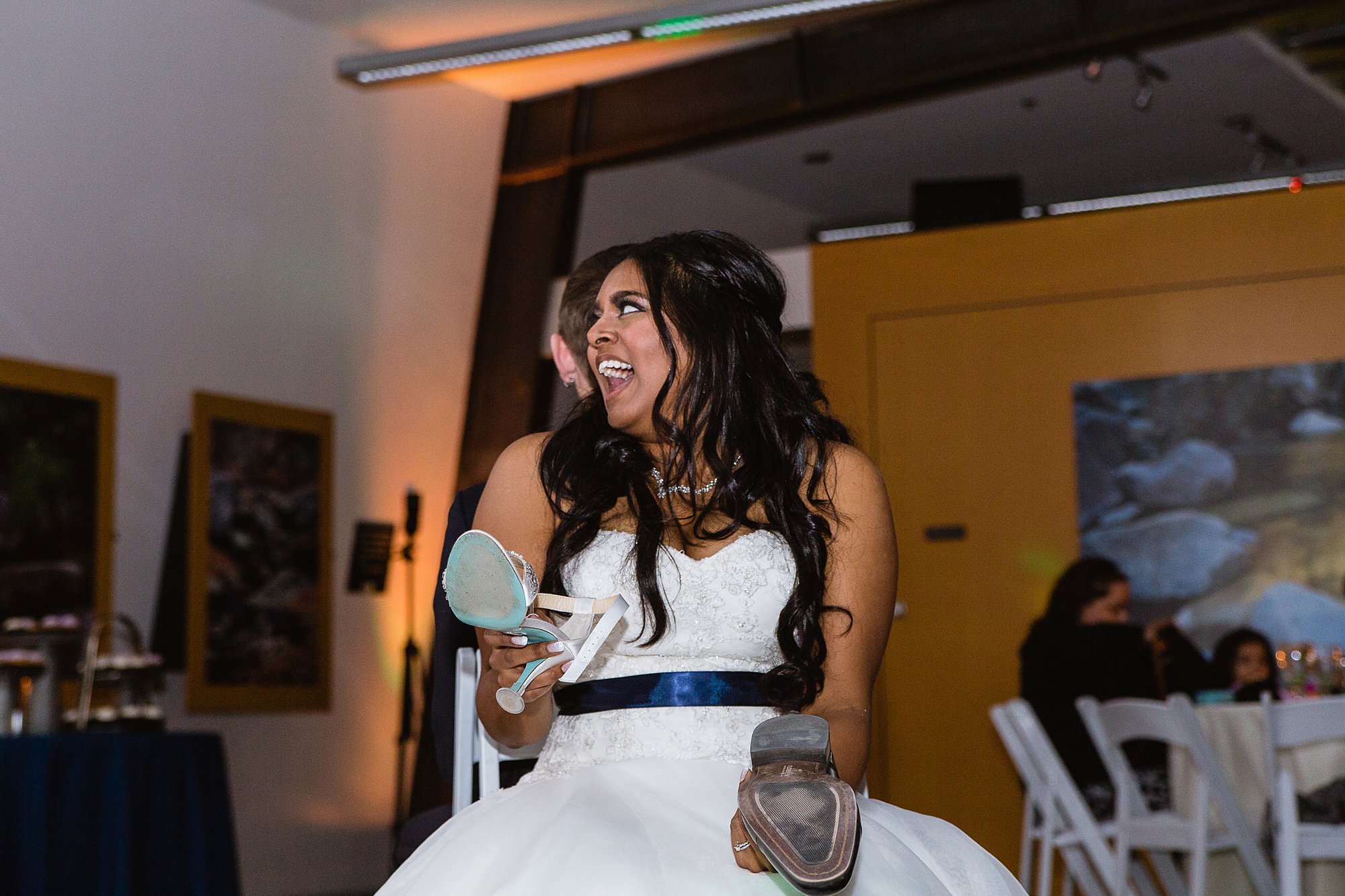 Bride laughing while playing the shoe game at reception at the Rio Salado Audubon center by Phoenix wedding photographer PMA Photography.