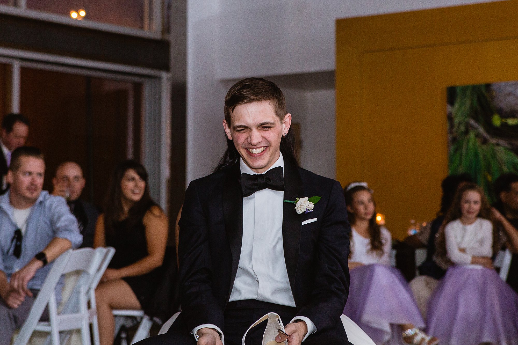 Groom laughing while playing the shoe game at their reception at the Rio Salado Audubon center by Phoenix wedding photographer PMA Photography.
