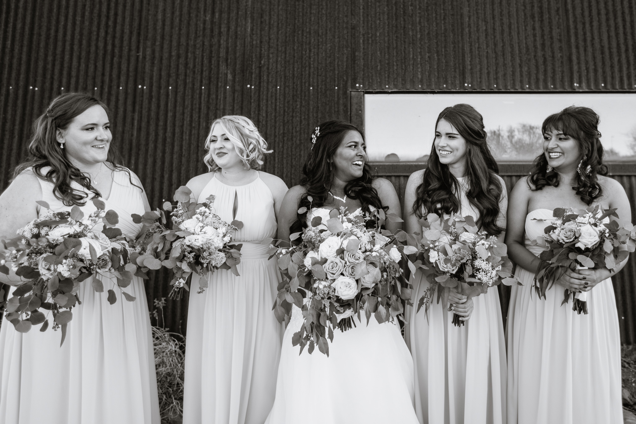 Black and white image of bride laughing with bridesmaids at the Rio Salado Audubon Center by wedding Photographer PMA Photography.