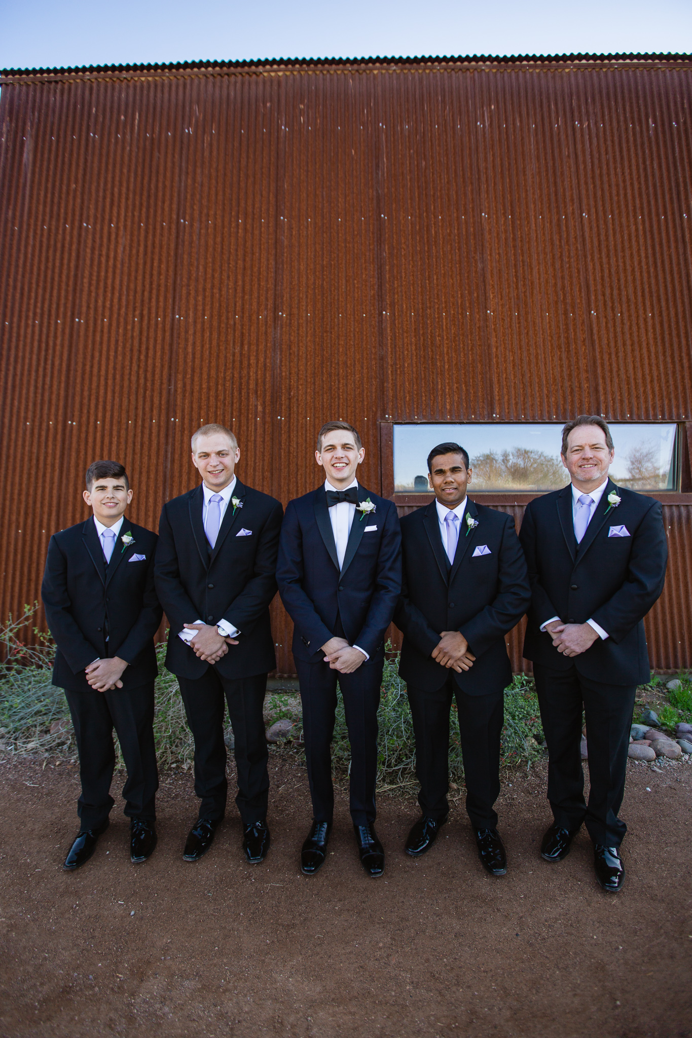 Groom with groomsmen in black suits with lavender ties at the Rio Salado Audubon Center by Phoenix wedding photographers PMA Photography.