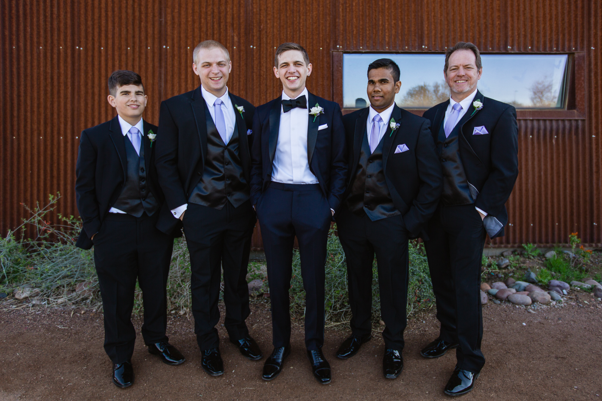 Groom with groomsmen in black suits with lavender ties at the Rio Salado Audubon Center by Phoenix wedding photographers PMA Photography.