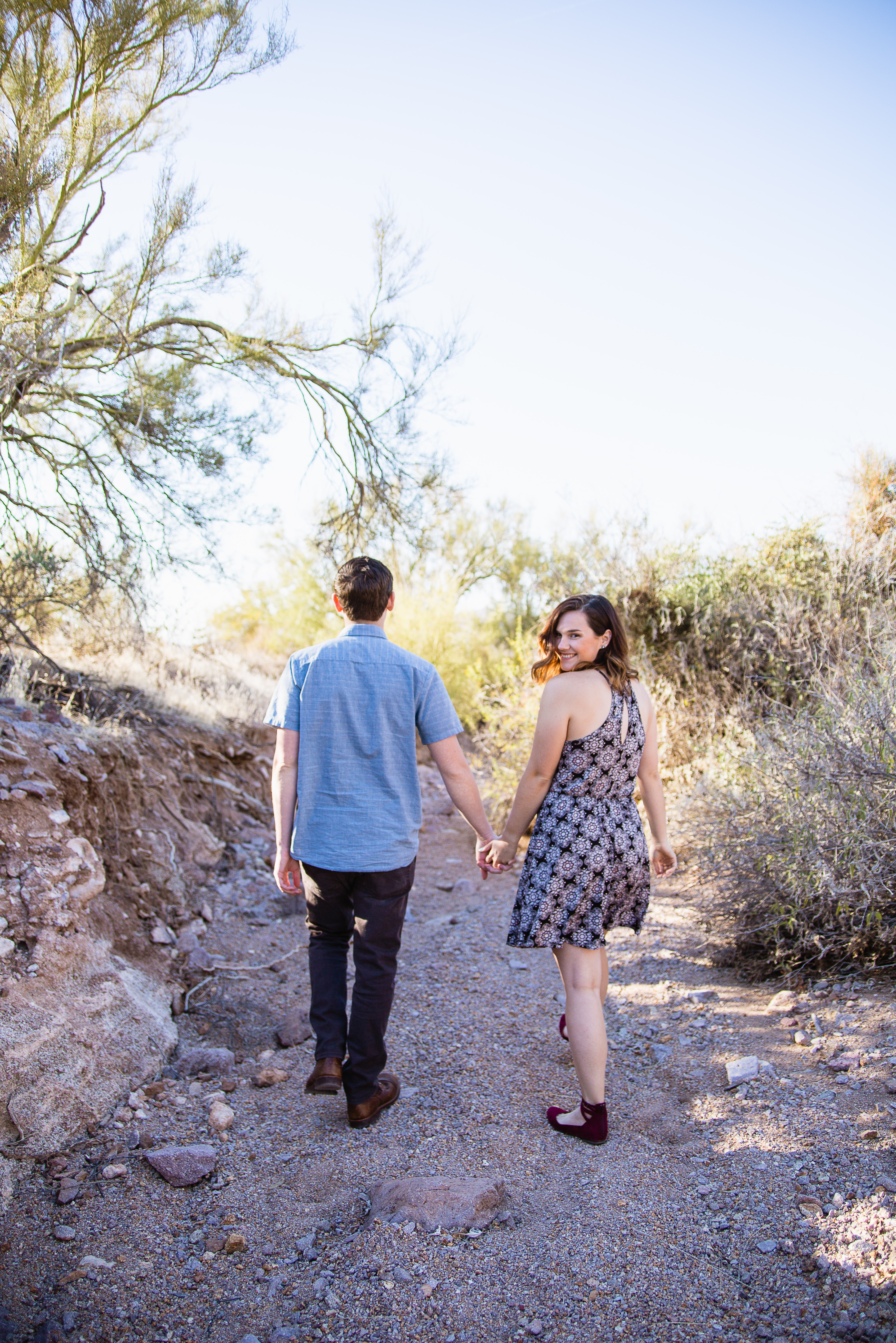 Couple walking through a desert wash engagement session at Lost Dutchman State Park by engagement photographer PMA Photography.
