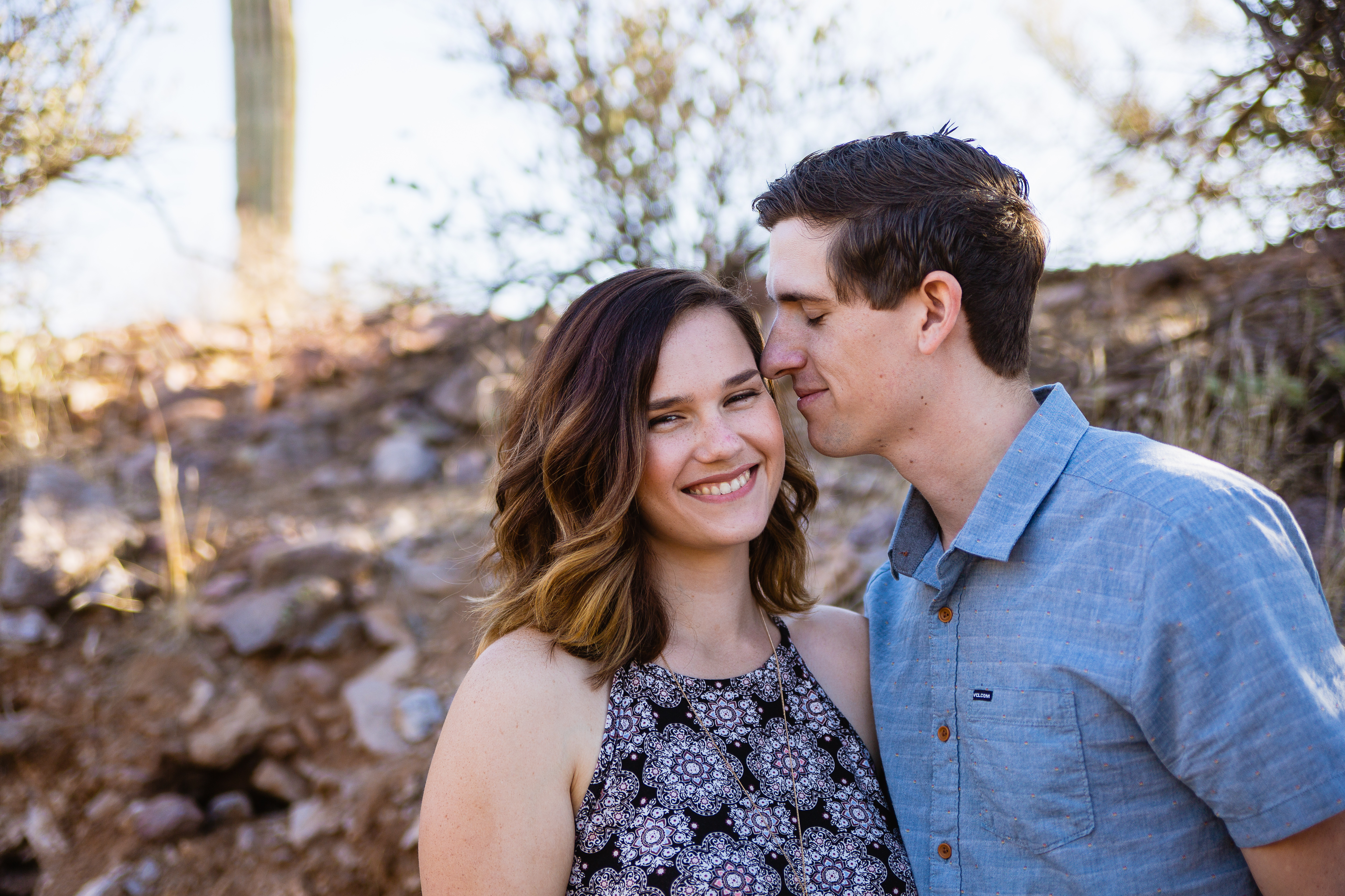 Fiance snuggling temple during desert engagement session at Lost Dutchman State Park by Phoenix wedding photographers PMA Photography.